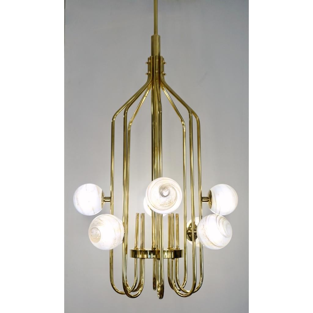 A contemporary innovative custom modern chandelier, entirely handcrafted in Italy. The handmade geometric cylinder brass structure, resembling a sleek birdcage, has a very organic curvilinear shape decorated with 8 round globes in an innovative