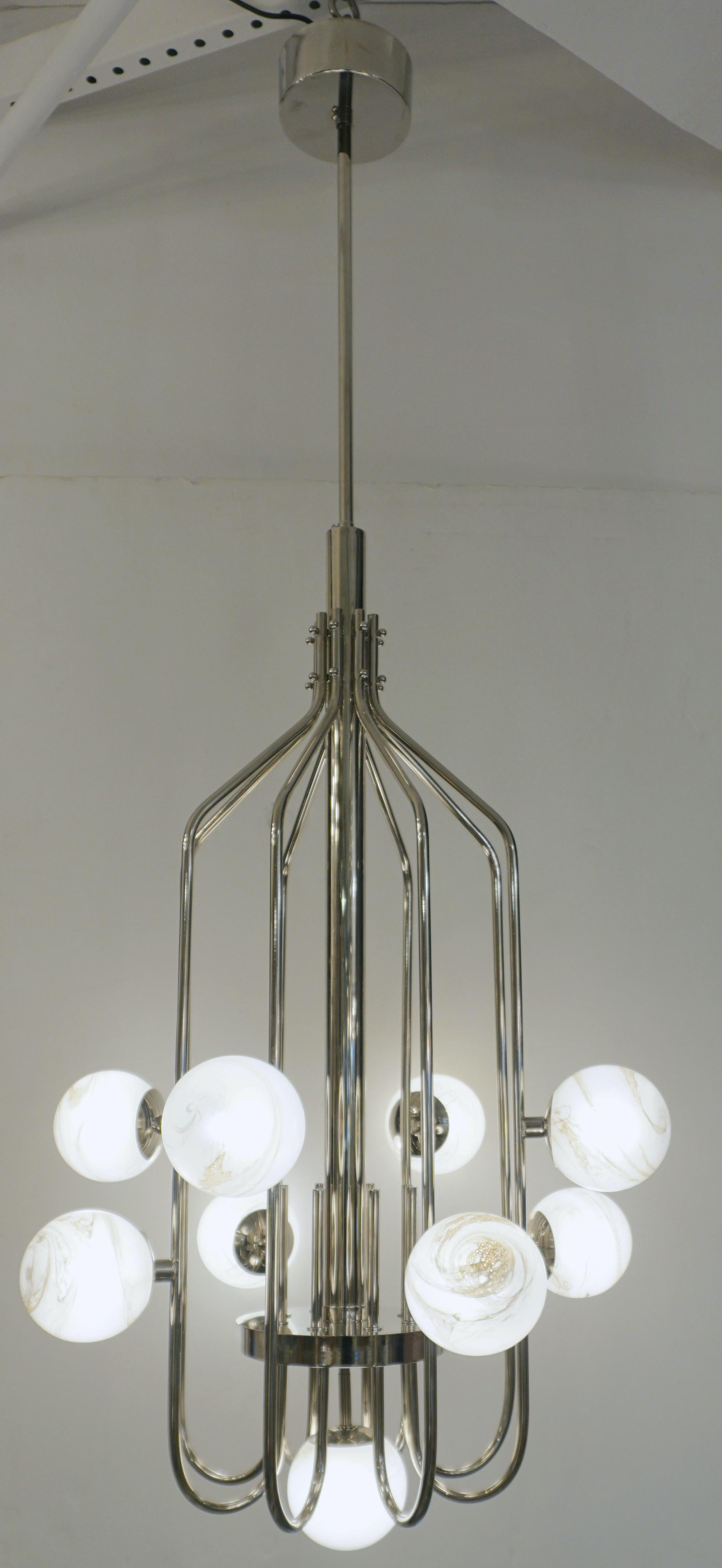 A contemporary innovative custom modern chandelier, entirely handcrafted in Italy. The handmade geometric cylinder nickel structure, resembling a sleek birdcage, has a very organic curvilinear shape decorated with 9 round globes in an innovative