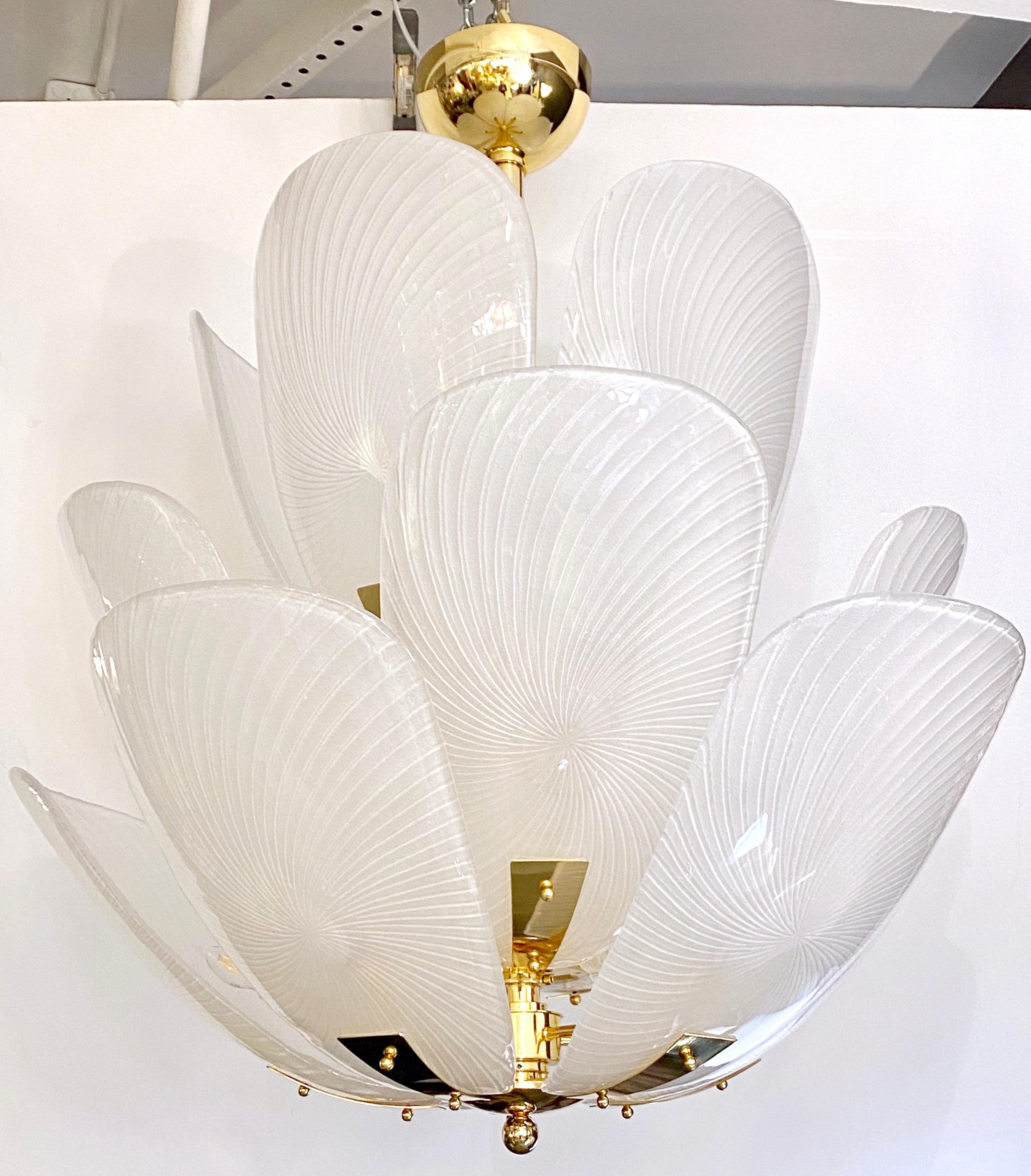 A contemporary creation of the highest quality and sophistication, this lighting fixture, with Art Deco Design and Hollywood regency flair, is entirely handmade in Italy, and composed of blown white Murano glass leaves, that are arranged in a lotus