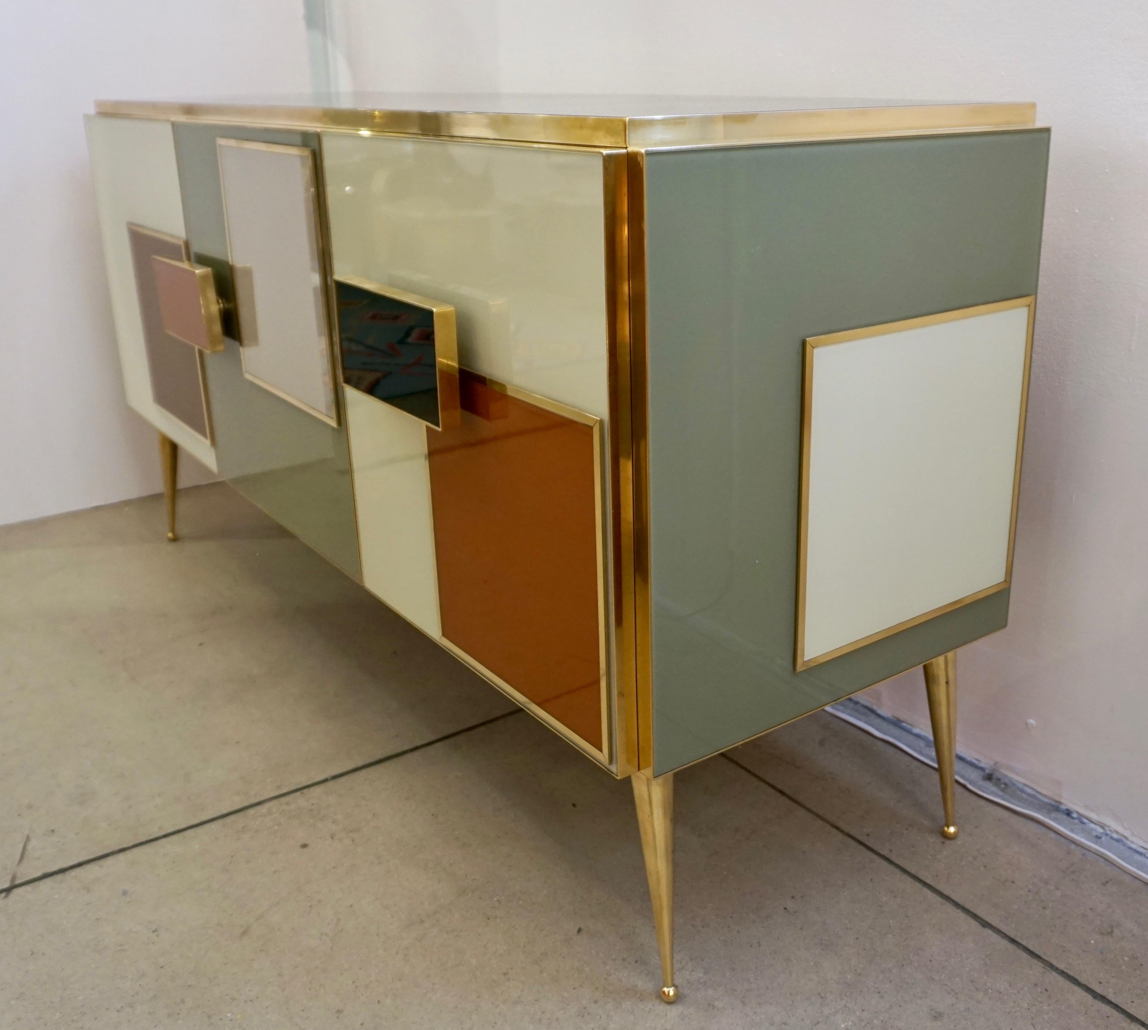 A contemporary creative 3-door modern credenza, entirely handmade in Italy, the surround in an attractive geometric decor that recalls Rothko's paintings, with raised art glass panels edged in brass, in different colors, ivory cream white, black,