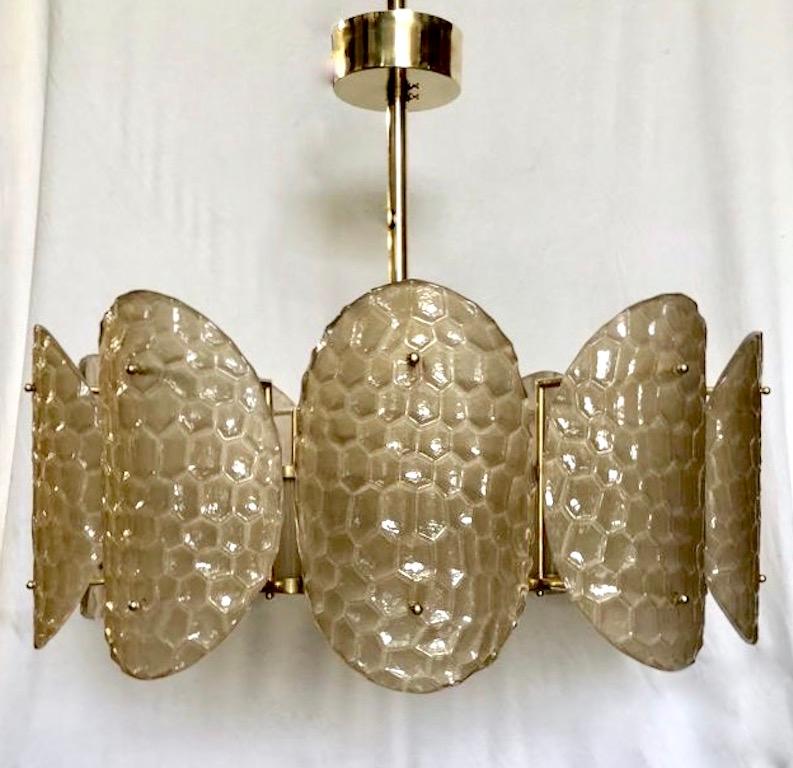 A contemporary custom organic modern chandelier, entirely handcrafted in Italy, with a handmade brass double frame with Art Deco flair.
The exterior is formed by nature-inspired oval convex elements resembling sea turtle backs in blown textured
