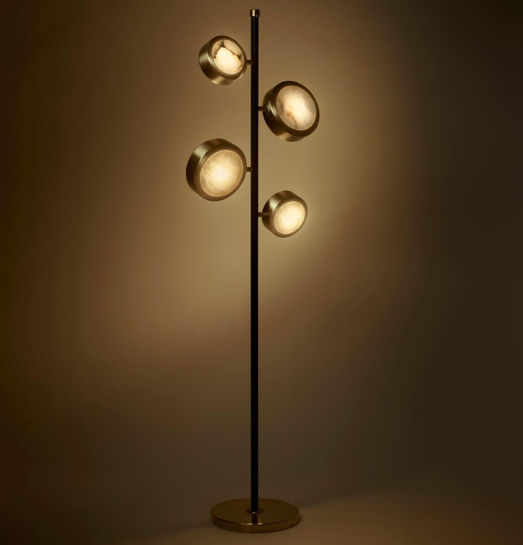 Elegant and sculptural, the Orion floor lamp captivates with its harmonious composition and contemporary allure. Four circular alabaster dif- fusers, delicately framed in satin brass, extend from a slender matte black metal stem, evoking a sense of