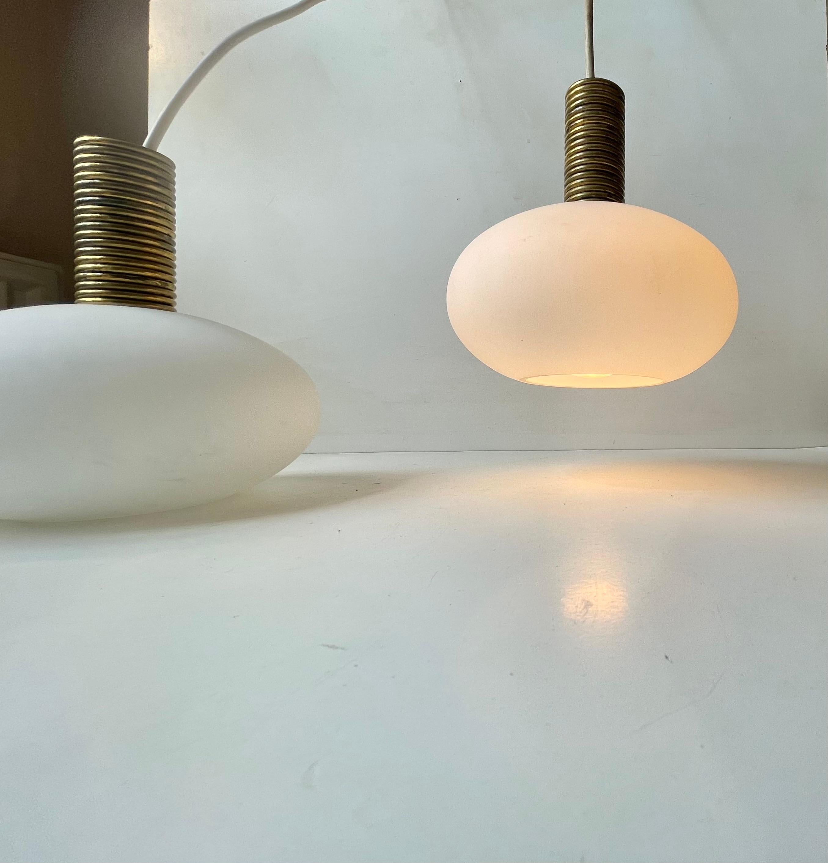 A stylish, unusual and bespoke pair of hanging lamps composed of frosted white glass and decorative tops made from brass rings. Unknown Italian maker/design, circa 1970-1980. Measurements: H: 20 cm, Diameter: 17 cm. The price is for the pair/set of