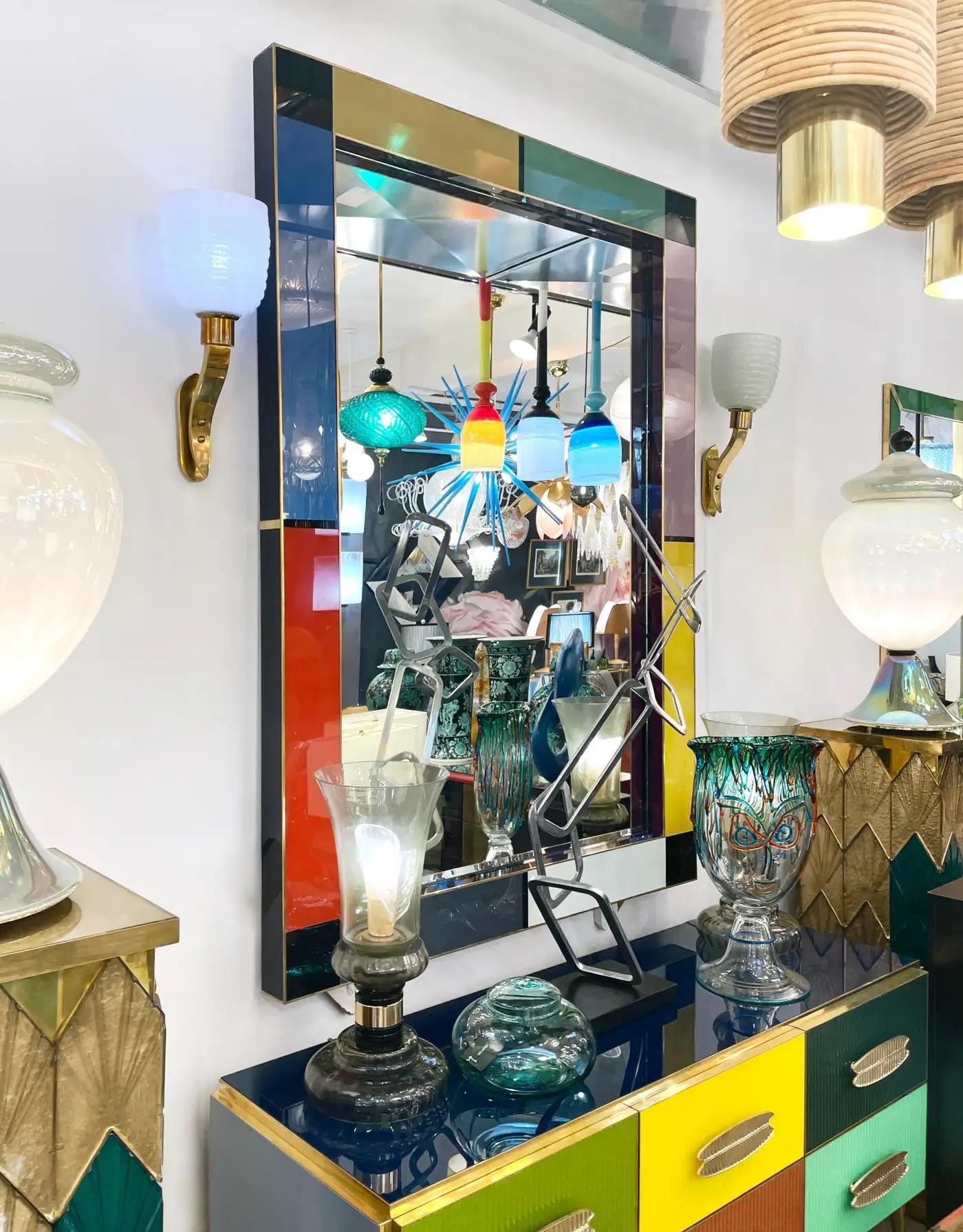 This one-of-a-kind modern mirror is a true work of art, meticulously handcrafted and custom-made in Italy with the utmost attention to detail, circa 2005. The 3D pop out frame, encased in brass, features a stunning geometric neo-plastic Memphis