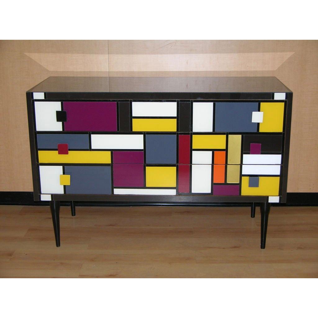 Contemporary Italian customizable 3-drawer chest of modern graphic Pop design, entirely handcrafted with a Piet Mondrian inspired abstract decor, the surrounds covered in colored glass: dark wine plum on the sides, black on the top. The front is