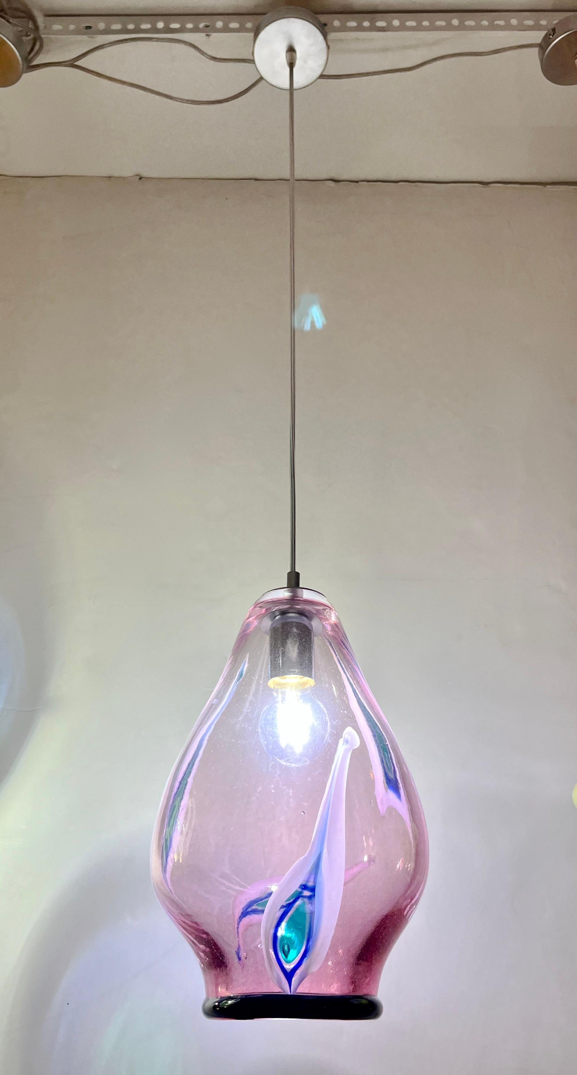 Fun and elegant Italian contemporary custom-made pendant chandelier, of organic modern design, entirely handcrafted with adjustable height, consisting of a sexy curved shade in translucent purple fuchsia blown Murano glass decorated with white, blu,