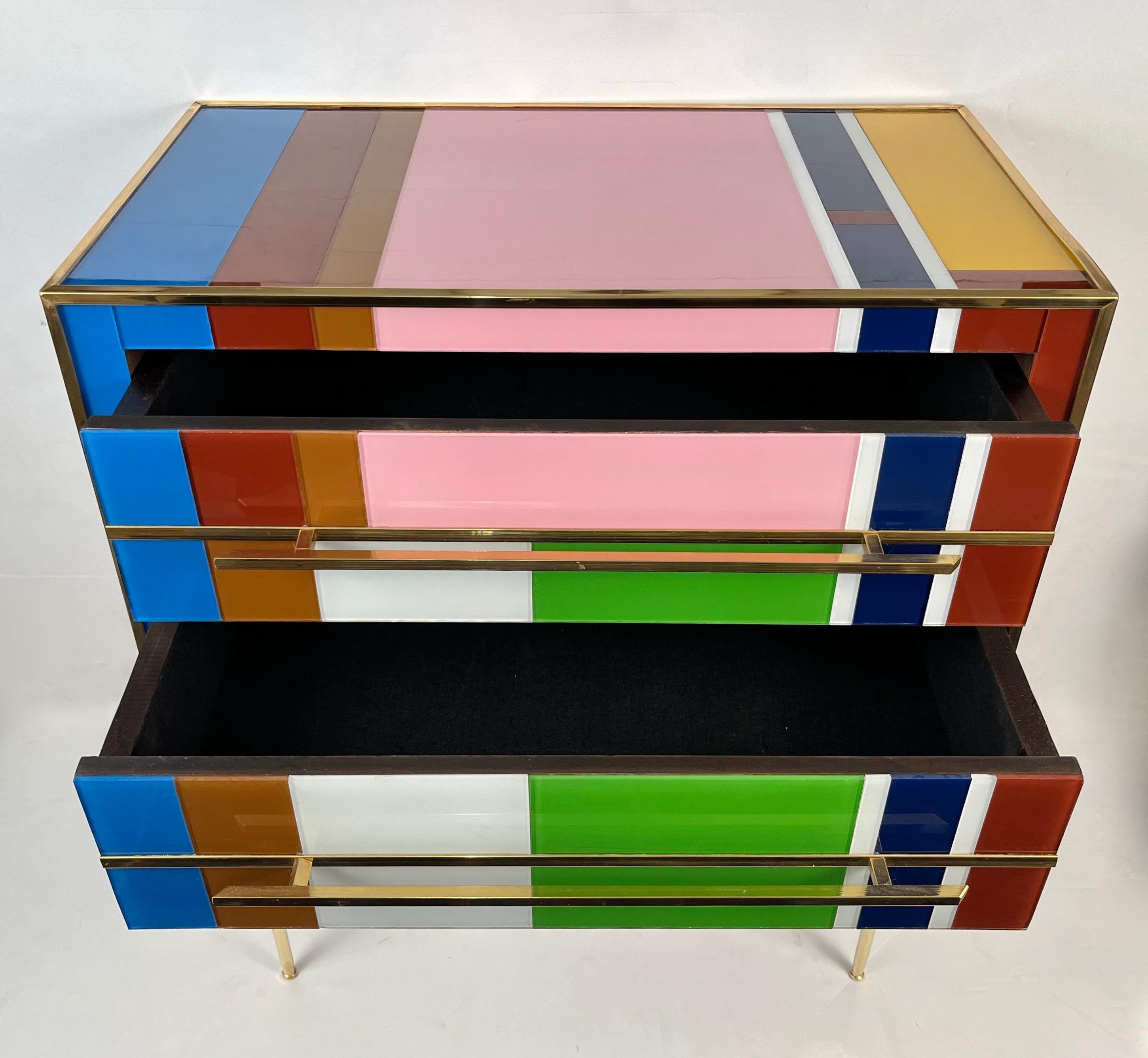 Contemporary customizable modern graphic pair of geometric Pop Art design two-drawer bedside tables / nightstands, entirely handcrafted in Italy, with a Piet Mondrian inspired abstract decor, the surrounds edged in brass are in colored glass: navy