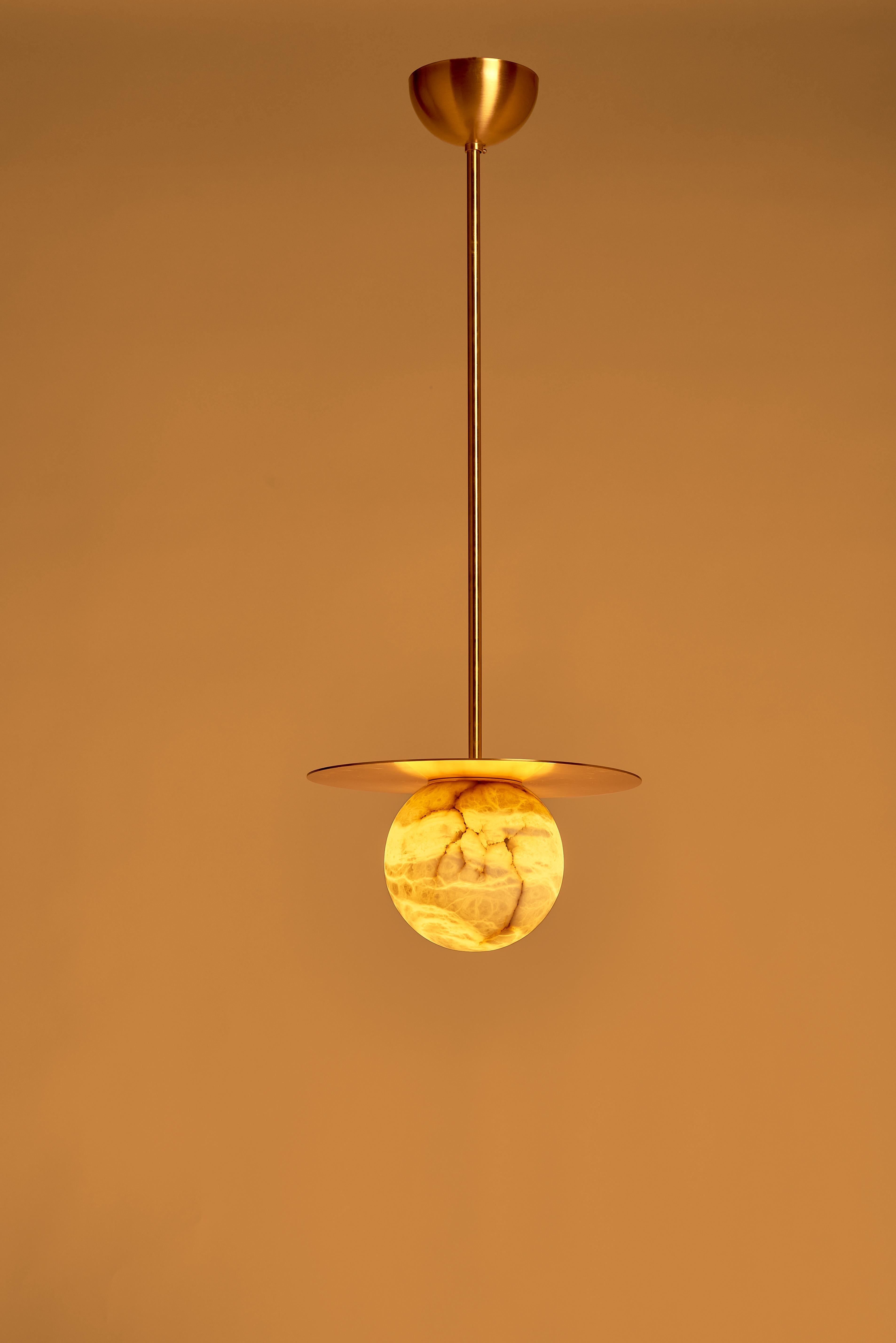 Combinant l'allure éthérée de l'albâtre et l'éclat chaleureux du laiton satiné, cette suspension est le complément idéal d'un intérieur raffiné. La lumière chaude brille sur les veines uniques de la pierre, créant un effet captivant, tandis que le