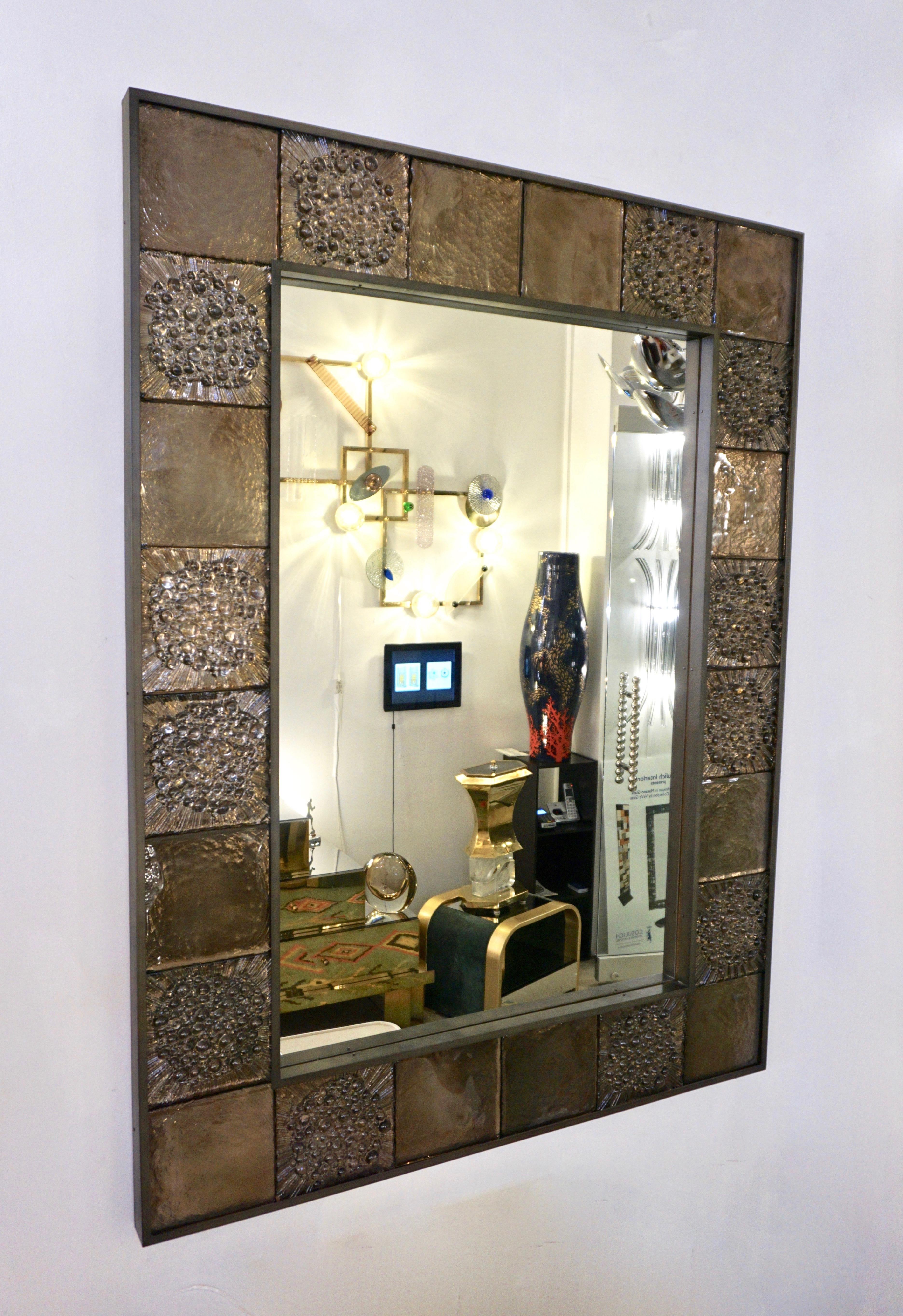 A contemporary customizable organic mirror with a sophisticated Industrial Design, entirely handcrafted in Italy, a sculpture piece with exceptional craftsmanship and innovative production: the decorative frame, inset in dark pewter bronze finish