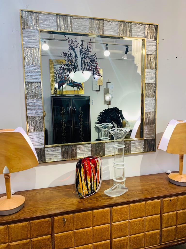 A contemporary geometric mirror with a sophisticated style, entirely handcrafted in Italy, a sculpture piece with exceptional craftsmanship and innovative production, customizable in sizes, finishes, and glass colors: the decorative frame, inset in