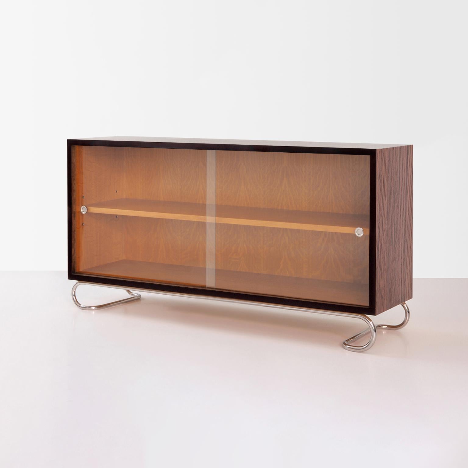 Bespoke low bookcase with case in veneered blockboard and sliding glass panels and tubular steel base.