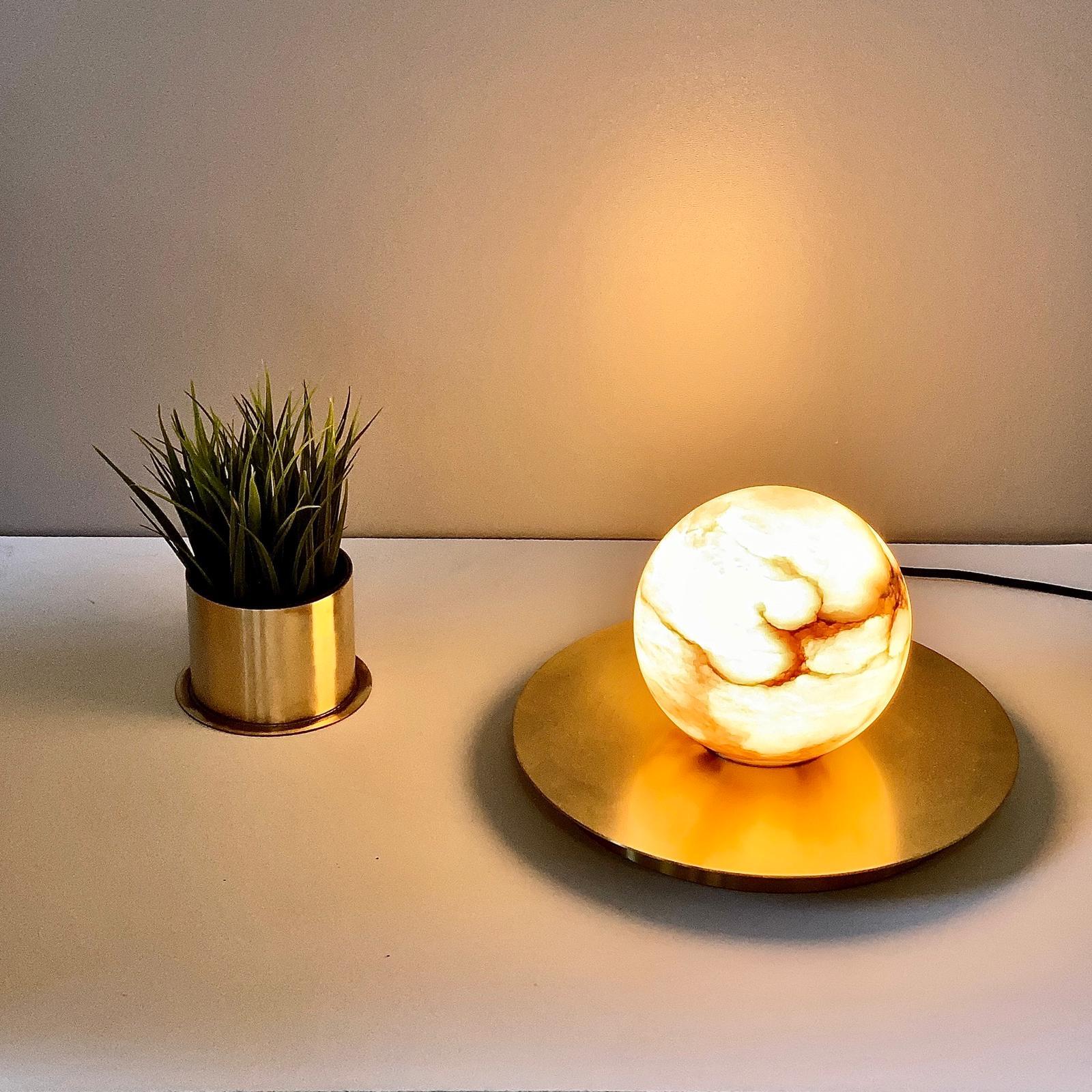 Cosulich interiors in collaboration with Matlight Studio, this organic table lamp, part of the Alabaster Moon collection, entirely handmade in Italy, emphasizes the properties of alabaster as a diffuser, with its warm color and texture of its amber