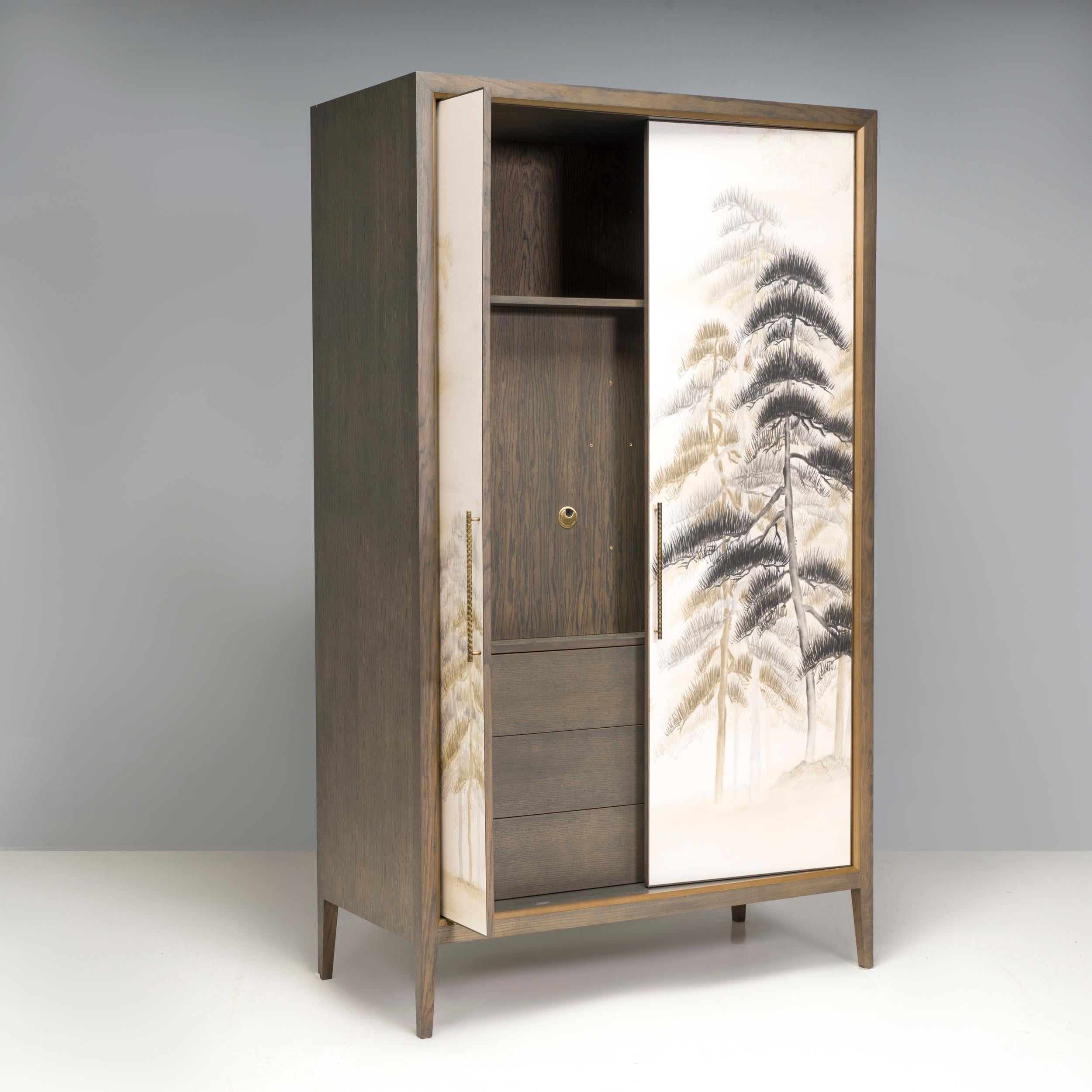An intriguing cabinet, crafted in wood with solid brass handles. There is brass detailing on the edges framing the dark wood.

A special technique of hand printed silk on its doors featuring Chinoiserie style landscape.  The softness and sensibility