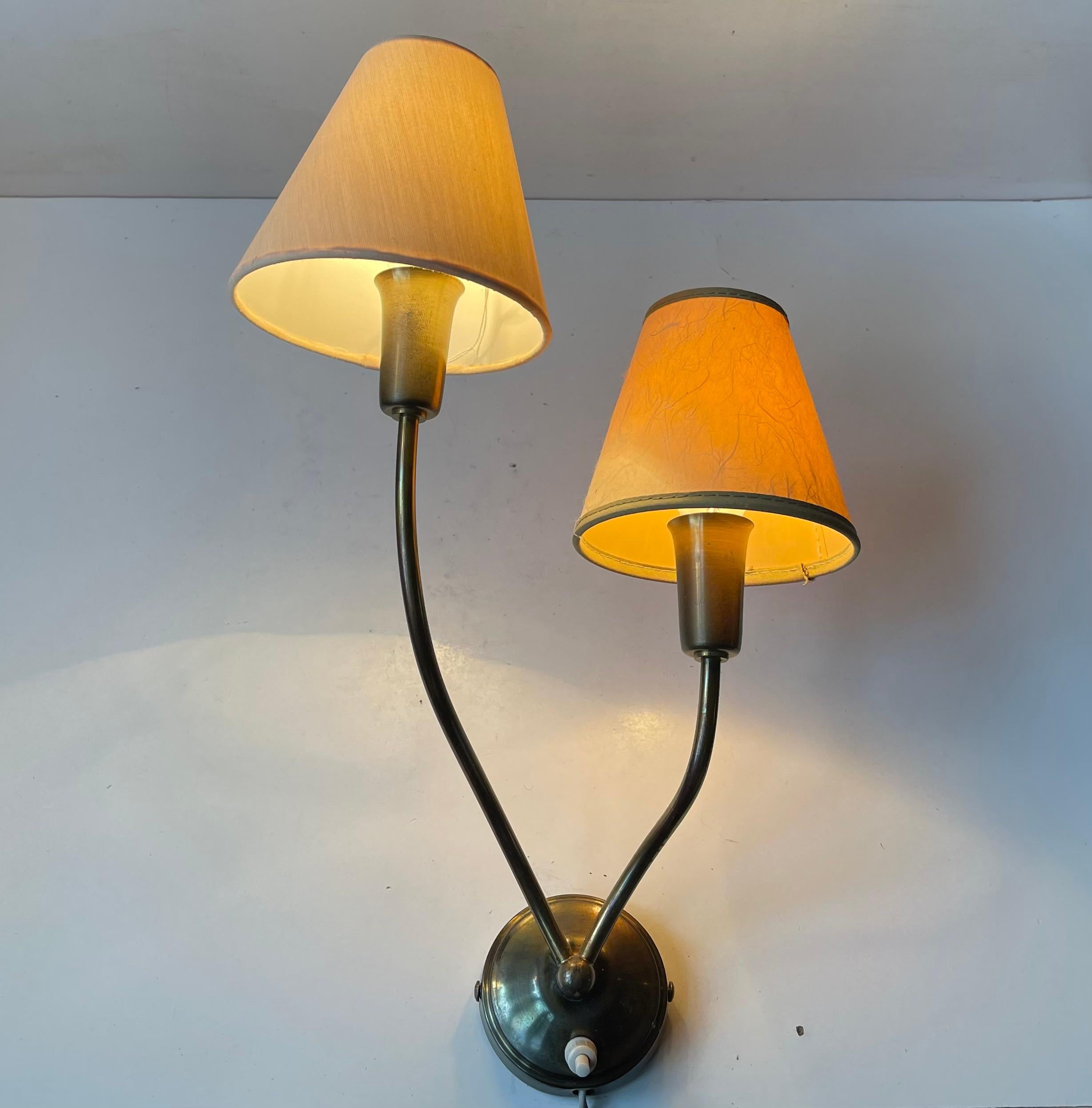 A flower inspired Italian double wall light in brass. Featuring two slightly diffrent textile shades and bakelite nipple on/of switch. Made in Italy during the 1950s. Measurements: H: 42/35 cm, Socket/mount diameter 9 cm.