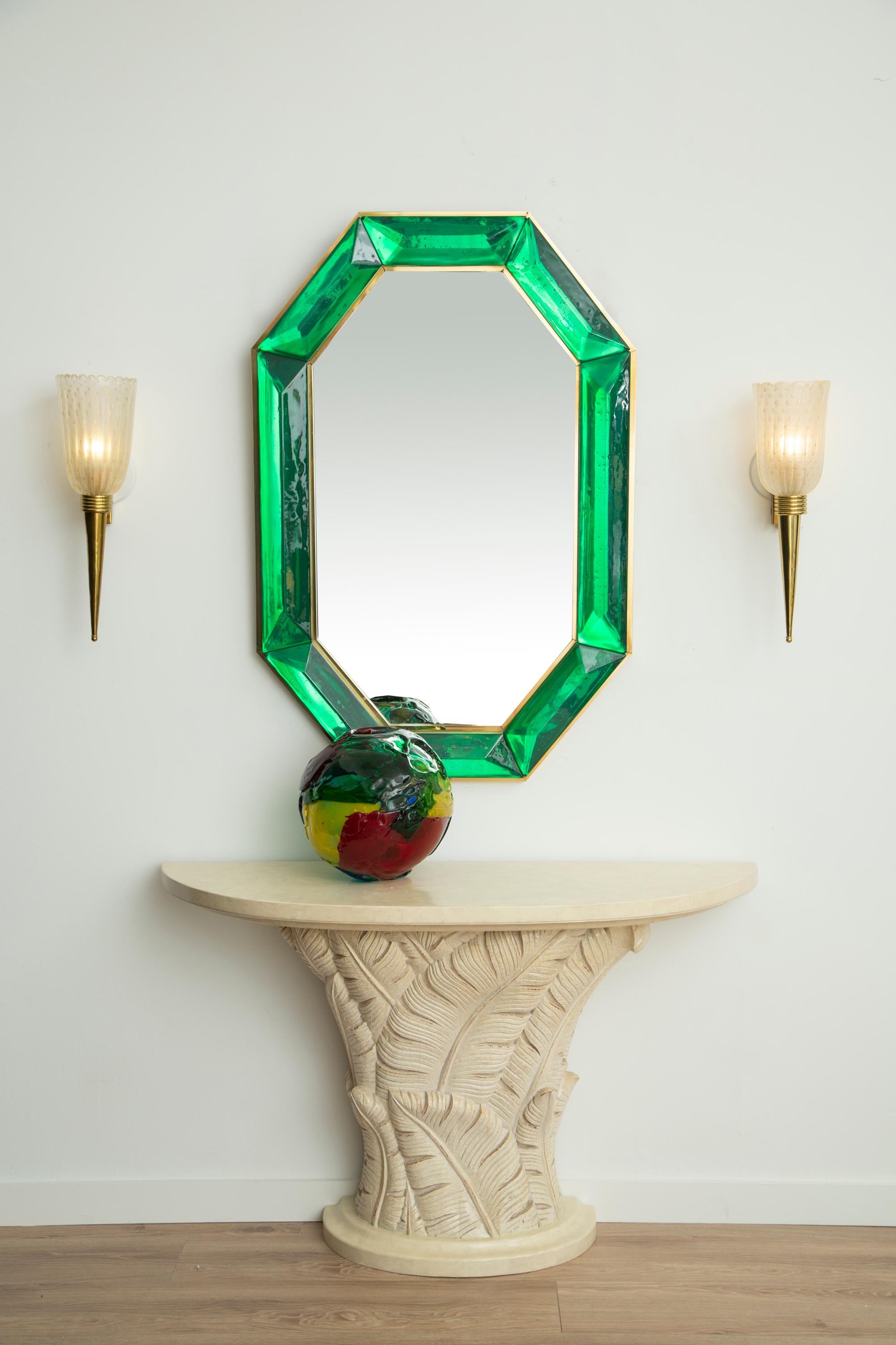 Bespoke octagon emerald green Murano glass mirror, in stock
 Vivid and intense emerald green glass block with naturally occurring air inclusions throughout 
 Highly polished faceted pattern
 Brass gallery all around
 Each mirror is a unique luxury