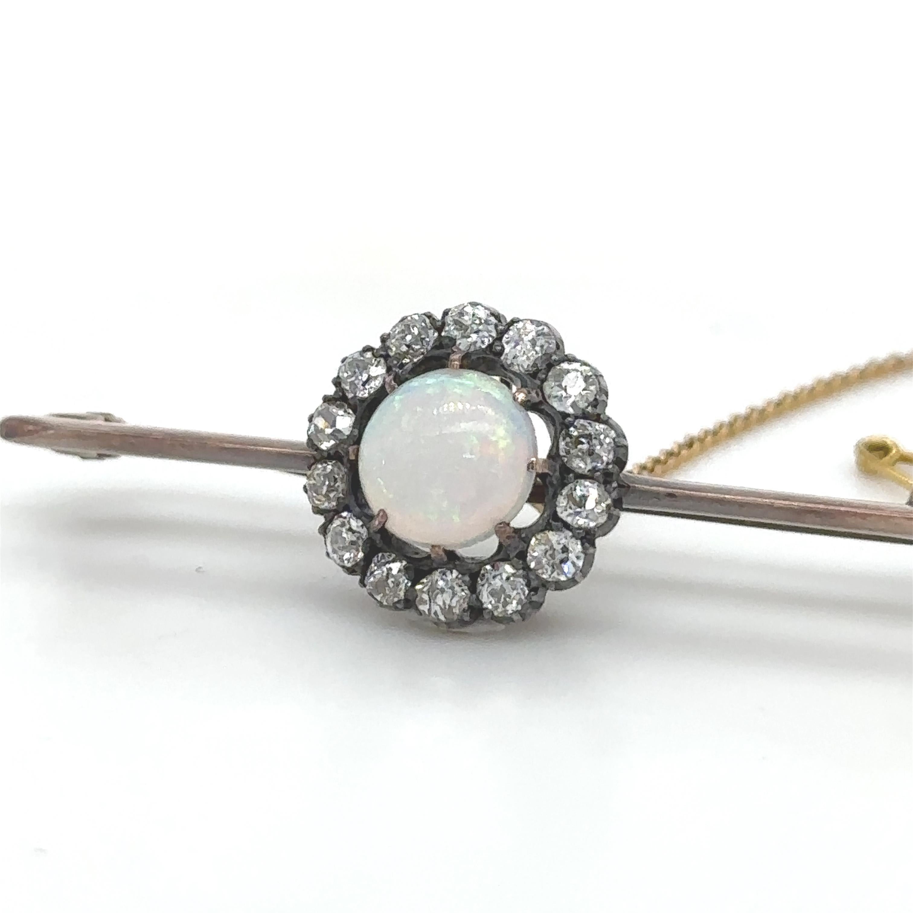 An Opal And Diamond Round Cluster Bar Brooch, with a round solid white crystal opal within a border of 14 old cut diamonds set in silver and 9ct rose gold.

Opal 1.00ct (estimated), 8mm round, 2.5mm depth, medium quality.

Diamonds 14 = 0.84ct