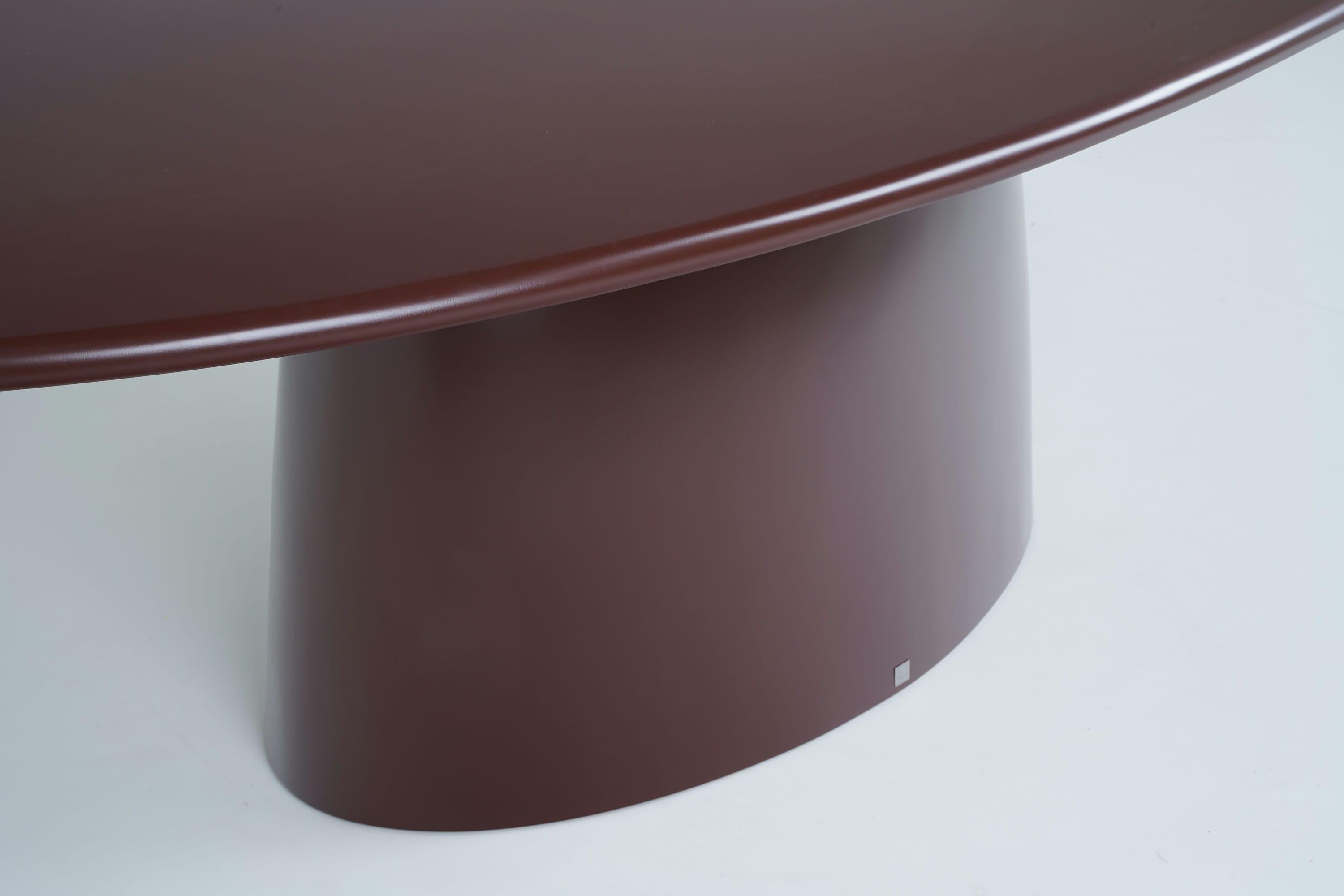 Il tavolo presenta un design sofisticato e minimalista, con una sorprendente silhouette ovale ellittica che crea un'estetica fluida e moderna. La base a piedistallo singolo aggiunge un elemento di sobria eleganza, consentendo al tavolo di fungere da