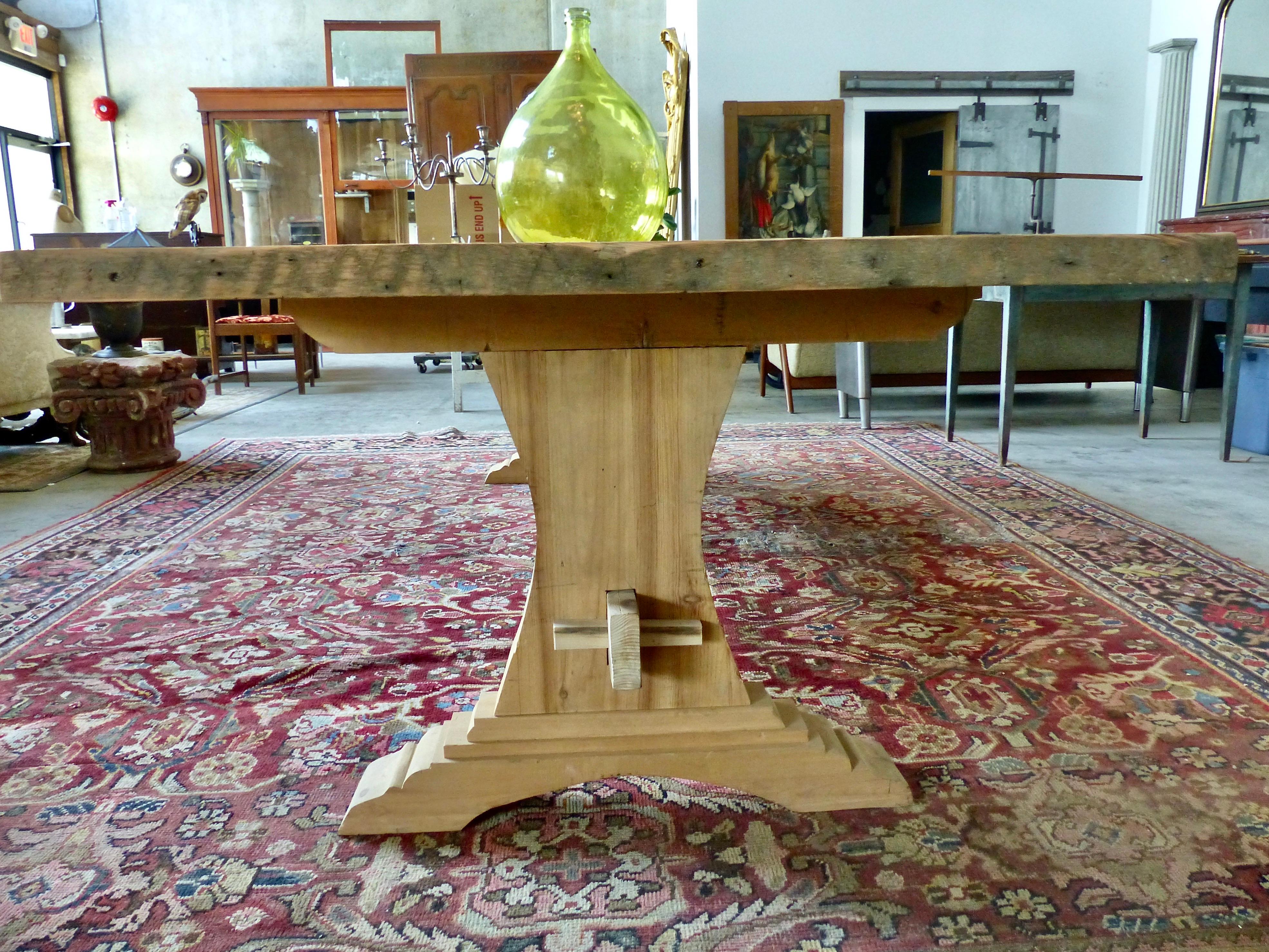 A 10-foot long trestle table made from reclaimed hemlock, salvaged from a building in Montreal. Plank top, decorative trestle-style legs from solid wood, and a beam for its stringer. Wood is left unfinished at this stage pending customers