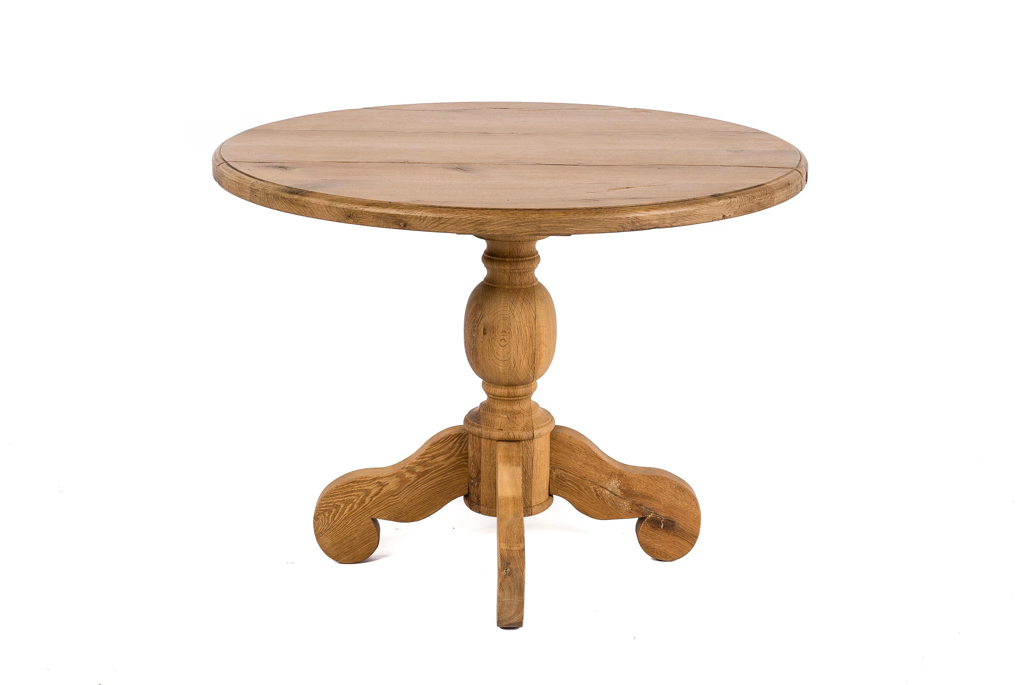 This round table has been made in our workshop by our experienced and skilled craftsmen. 
The table has a rustic top with a great grain pattern and cracks. The edge has a bullnose profile. 
It stands on a massive turned column on four scrolled
