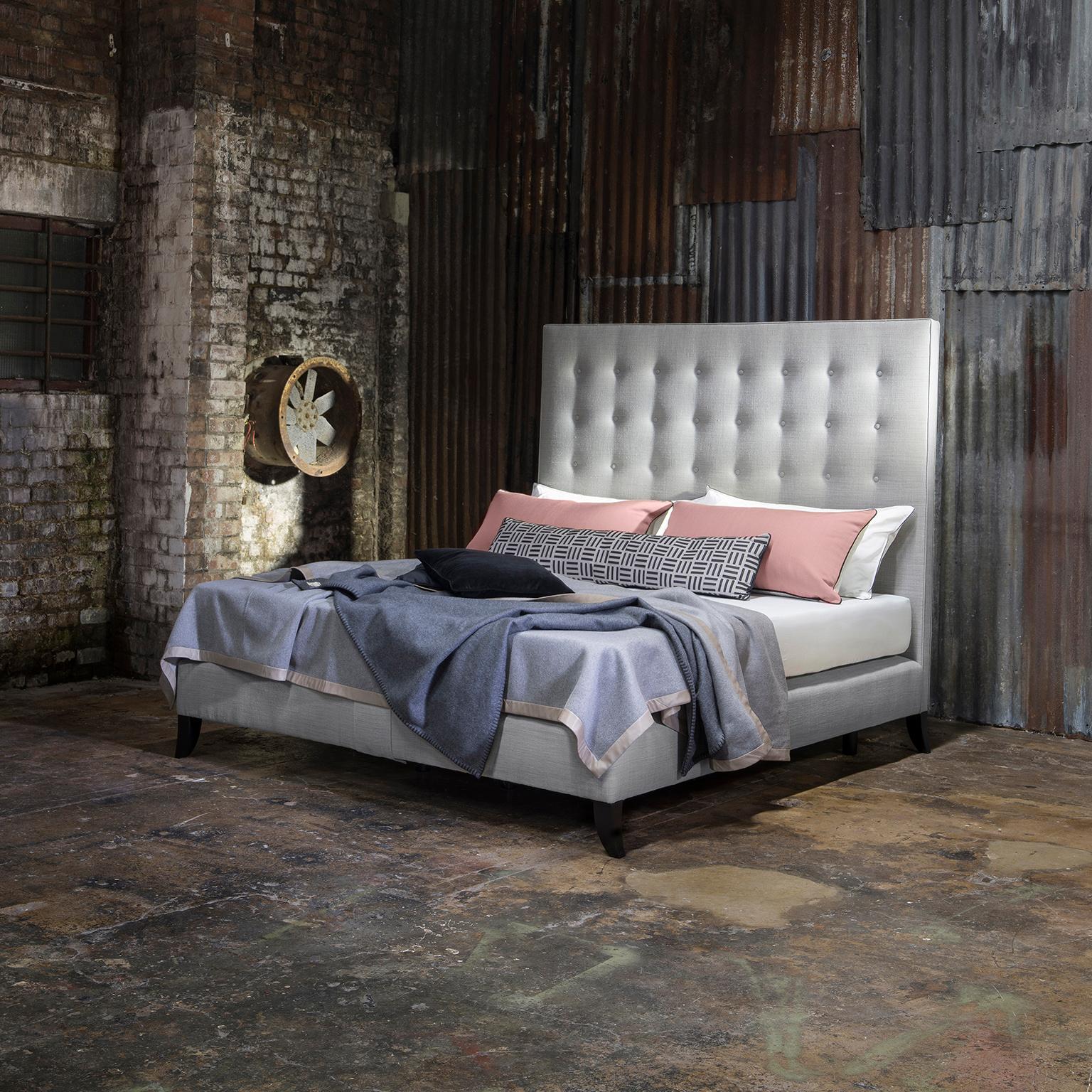 Featuring a statement headboard with Classic styling, the Holly bed oozes timeless style. The oversized headboard with its restrained buttoning and piped edge embraces a modern metropolitan feel. Upholstered in a subtle textured grey fabric from