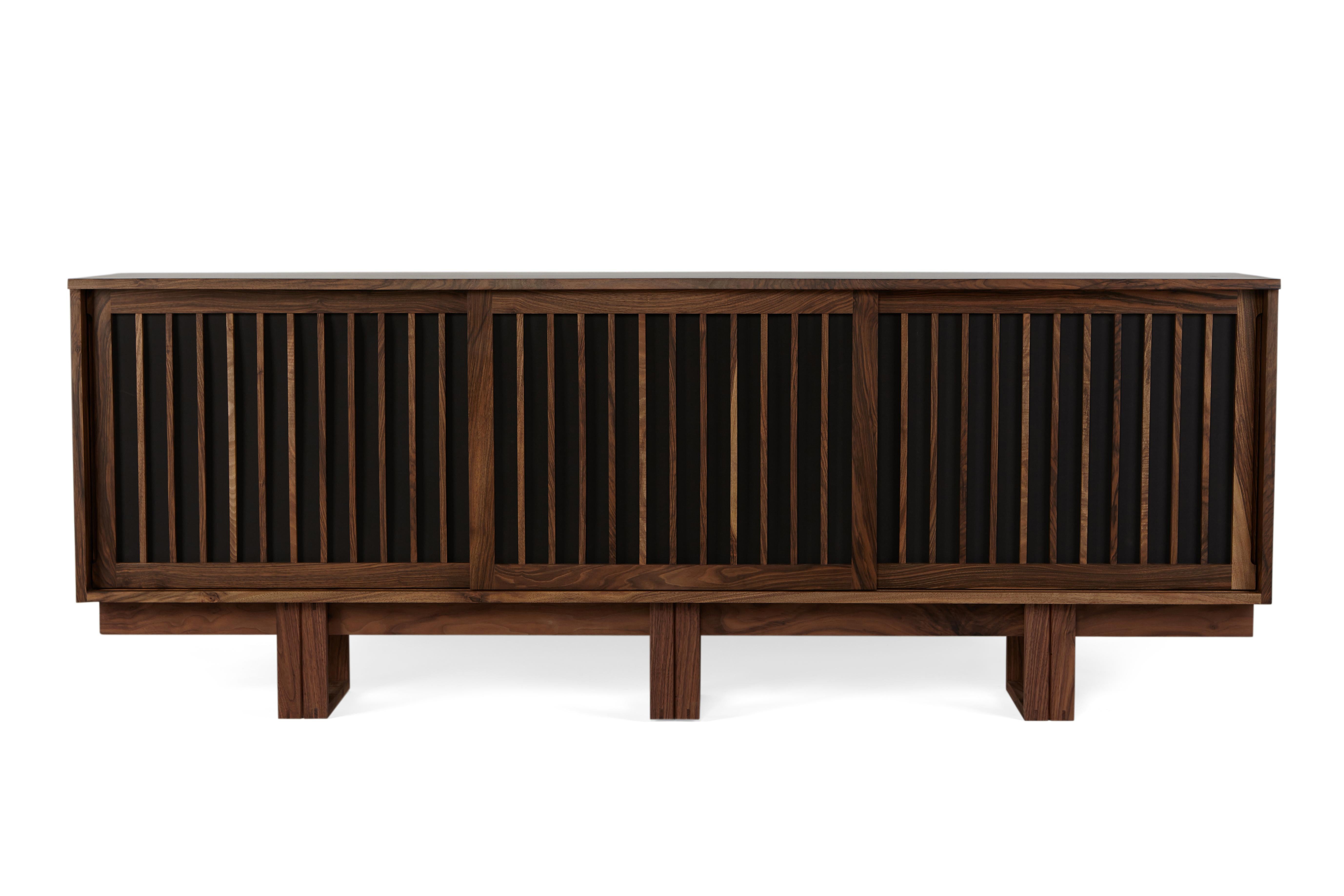 The design for this cabinet in solid walnut takes its inspiration from midcentury designer-makers such as George Nakashima.
It has three slatted sliding doors, which can either have paper or fabric backing panels, and the centre section has three