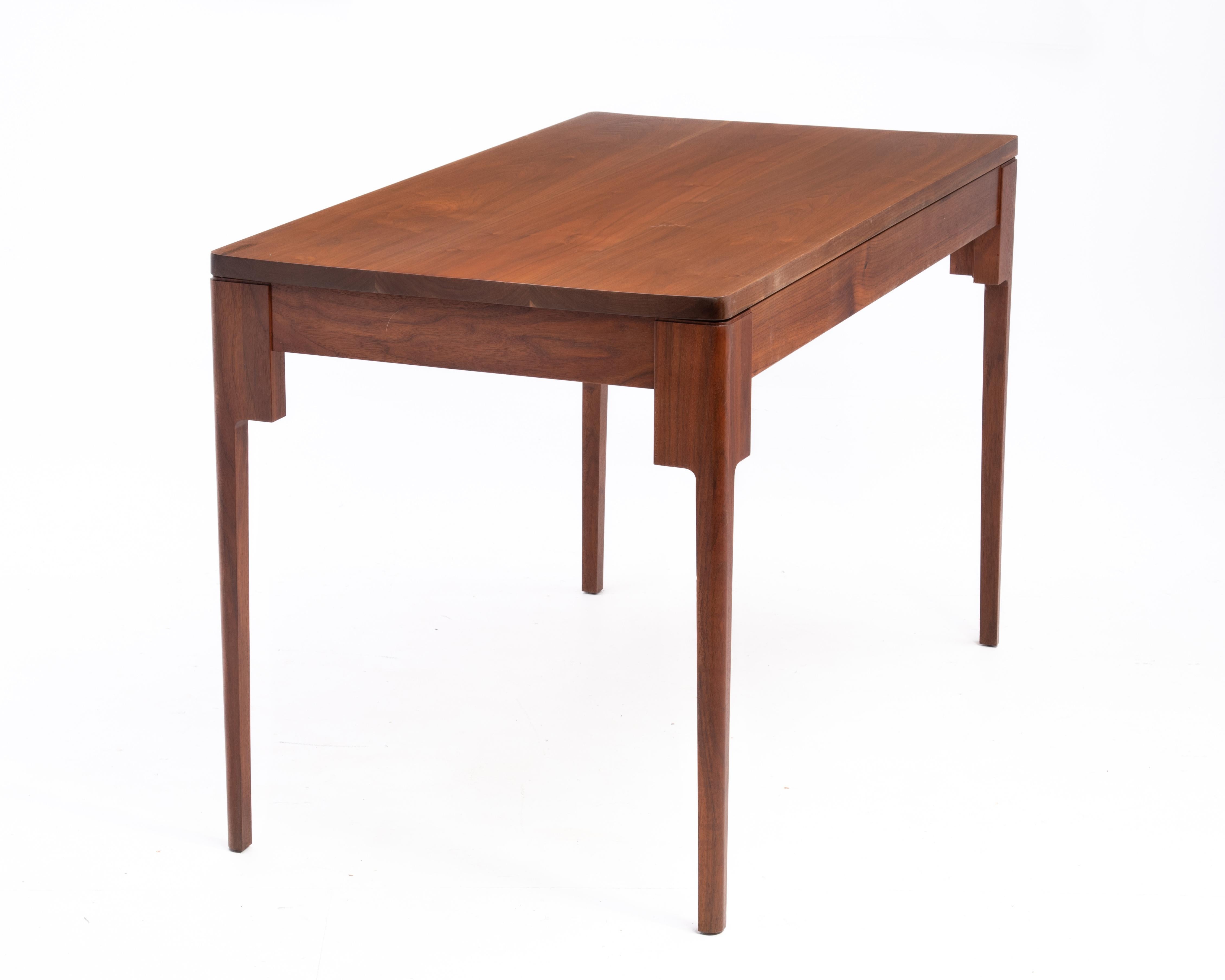 A one of a kind walnut writing table or desk that is large enough to serve as a dining table for four. The piece features solid walnut throughout, a floating top and tapered legs. Custom made, the design is both solid and light.