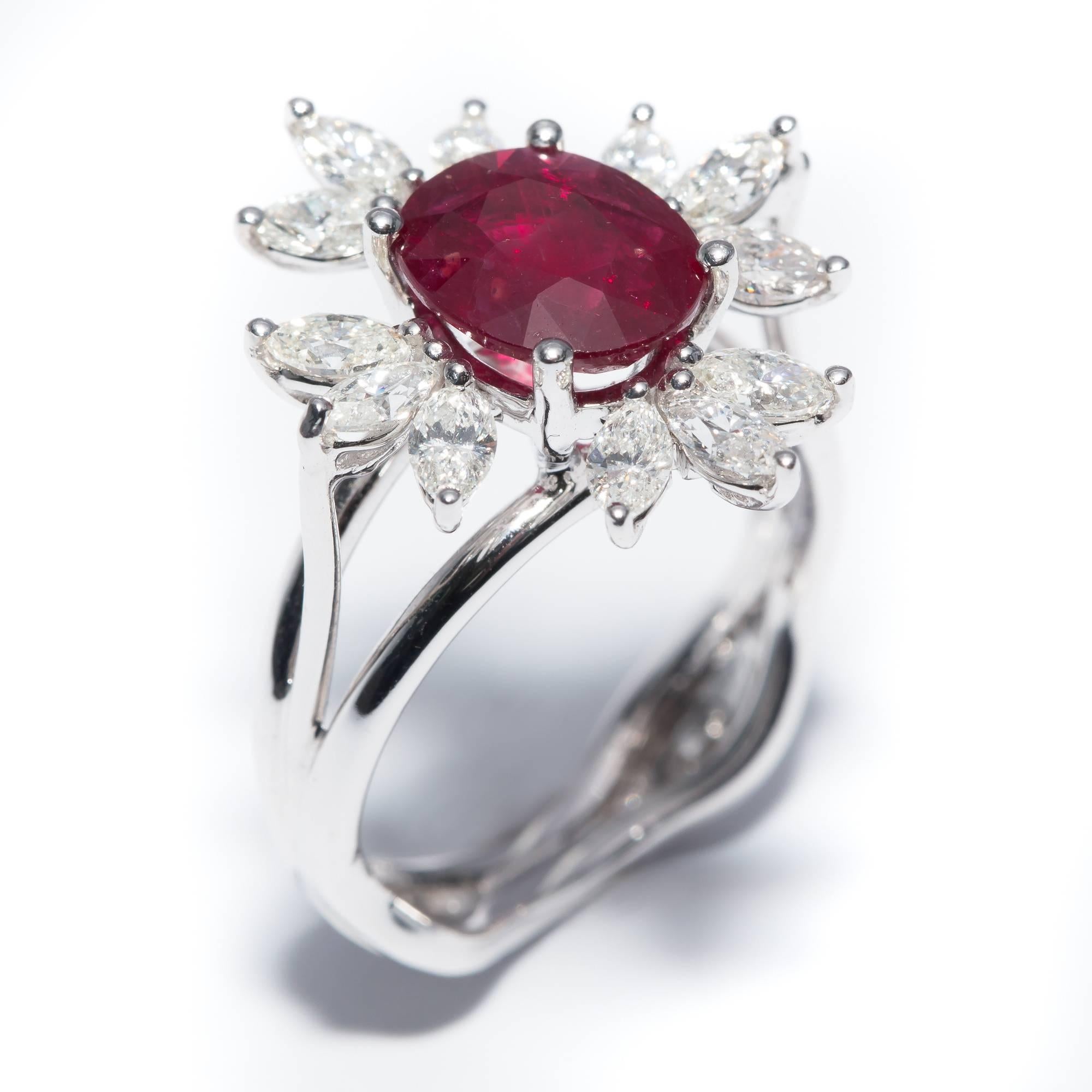 A custom revival of the traditional Halo design, this particular ring has a center stone surrounded by Marquise cut white diamonds totalling between 1.00 - 1.10 Carat with a 2.13 Carat Oval Shaped Ruby nice deep red color (9 x 7 mm) set in 18 Karat