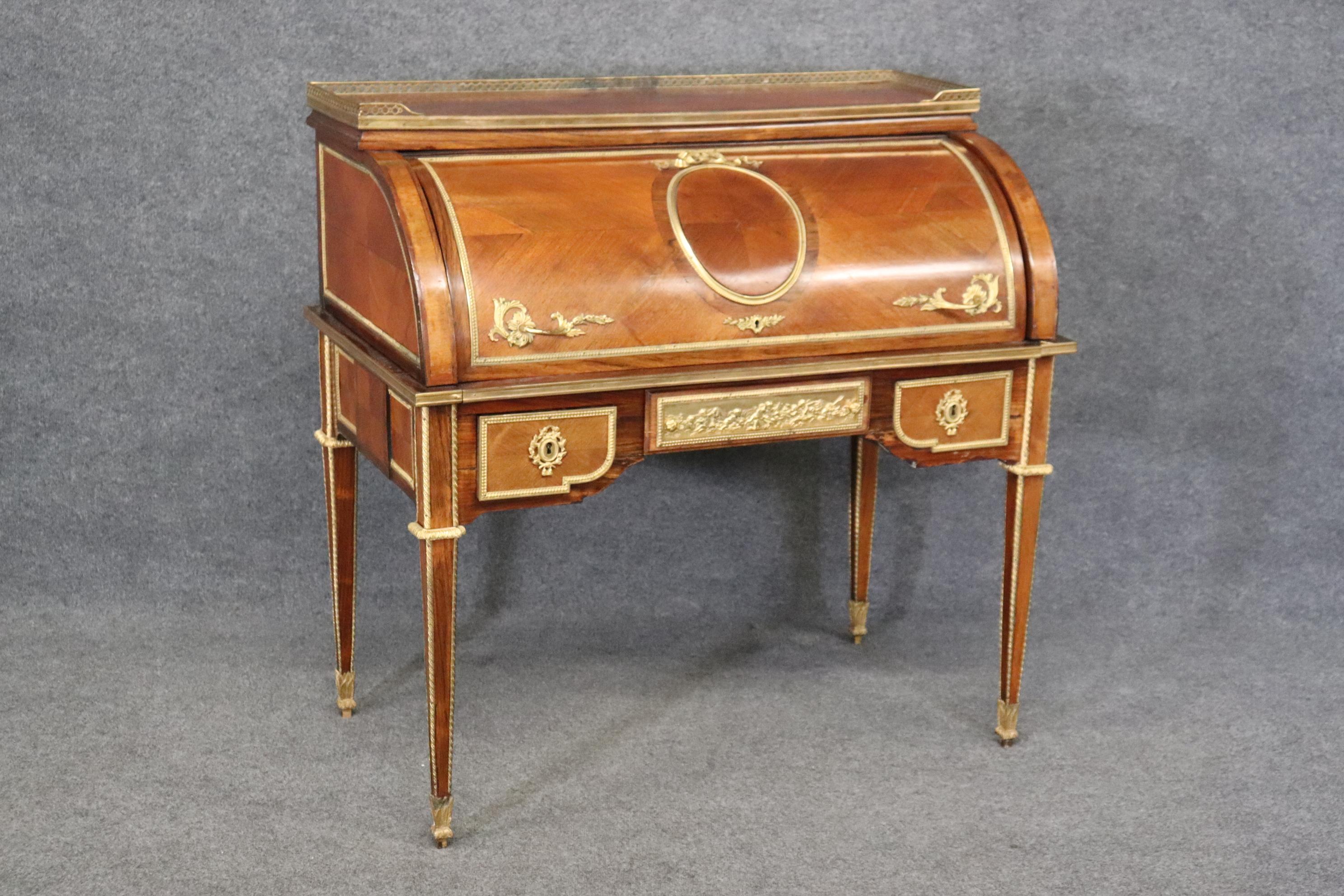 This is an absolutely stunning gold dore' bronze mounted cylinder desk with the best cherub or putti scenes and other bronze mounts that make it absolutely superb. The desk dates to the 1900s era or even earlier and is in good antique condition and
