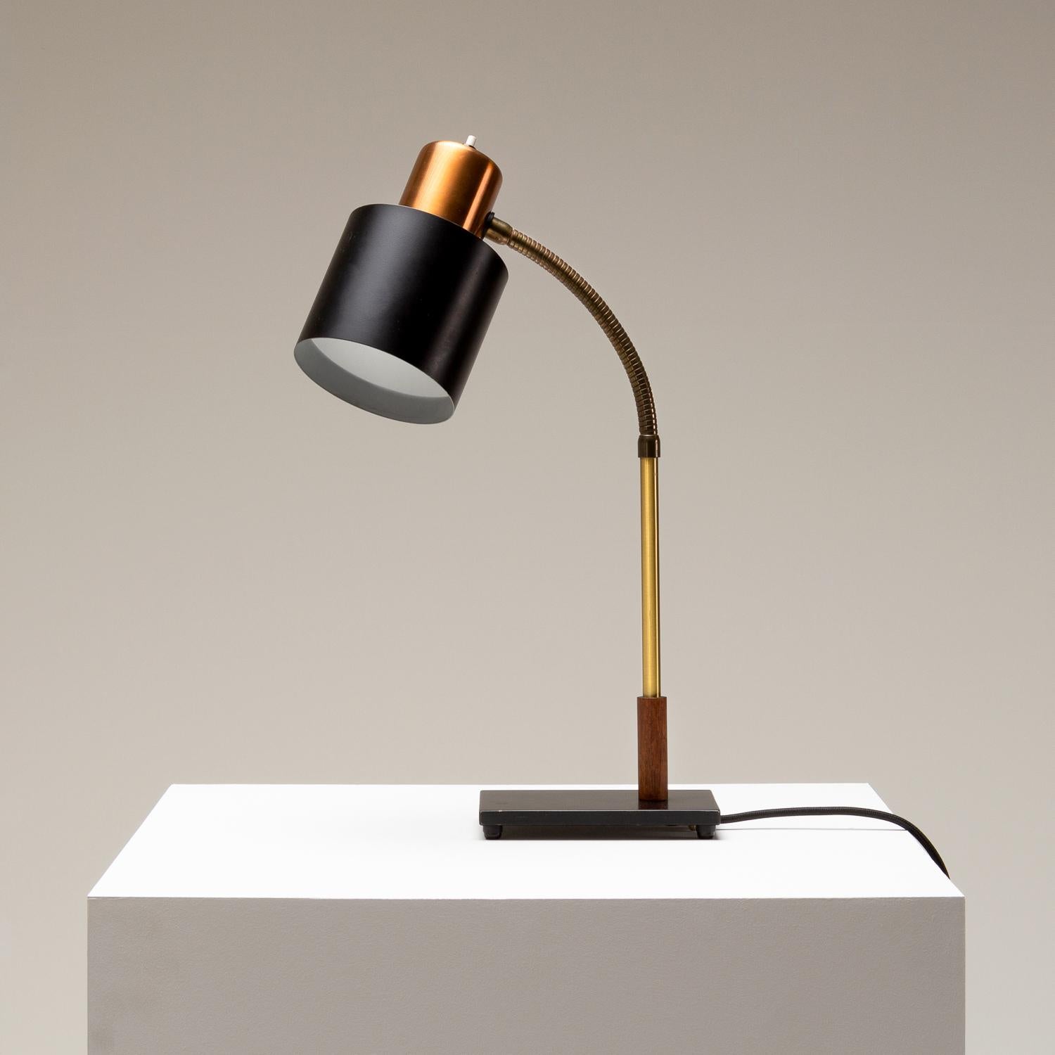 Beta desk lamp designed by Jo Hammerborg in the late 1950s for Fog & Mørup. Flexible brass neck with teak base detail. Copper and black lacquer shade and black footplate.
 
  