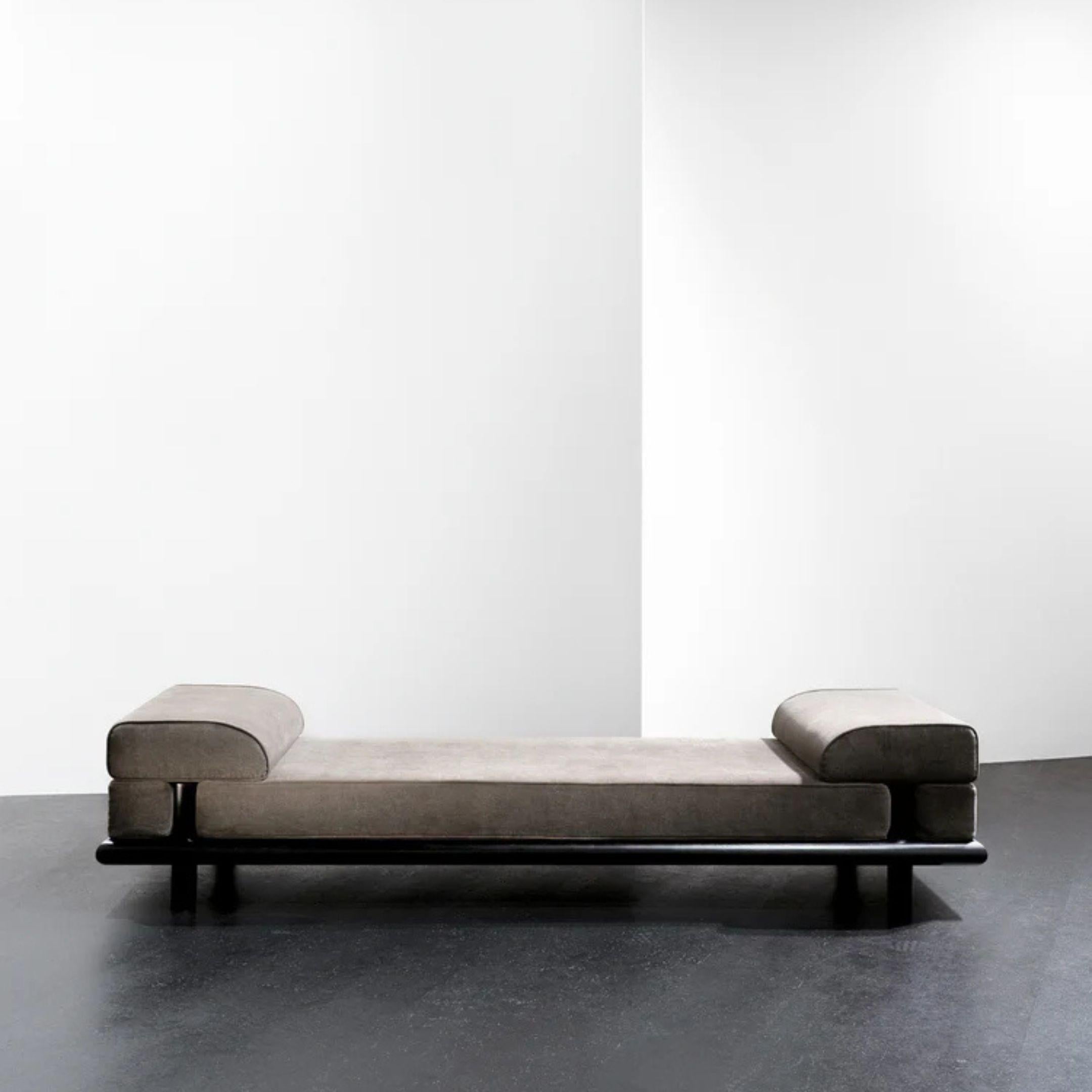 Beth est une pièce polyvalente conçue par Ann Demeulemeester qui fait office de canapé, de banc ou de lit de jour d'une longueur généreuse de 280 centimètres. Ses profils aux bords arrondis et son cadre en chêne teinté en noir reflètent une approche