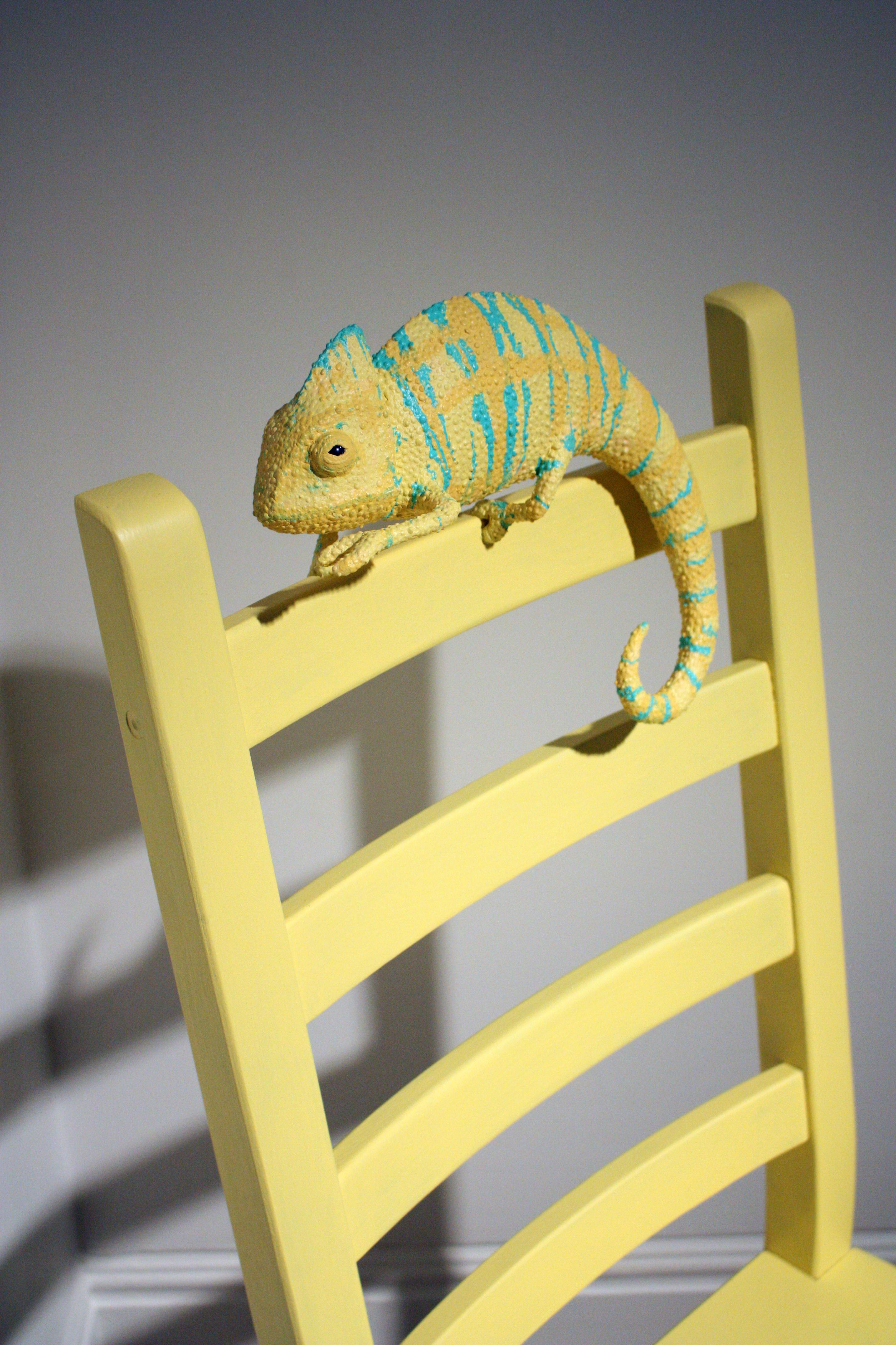 Camaleón de papel maché en una silla amarilla 
