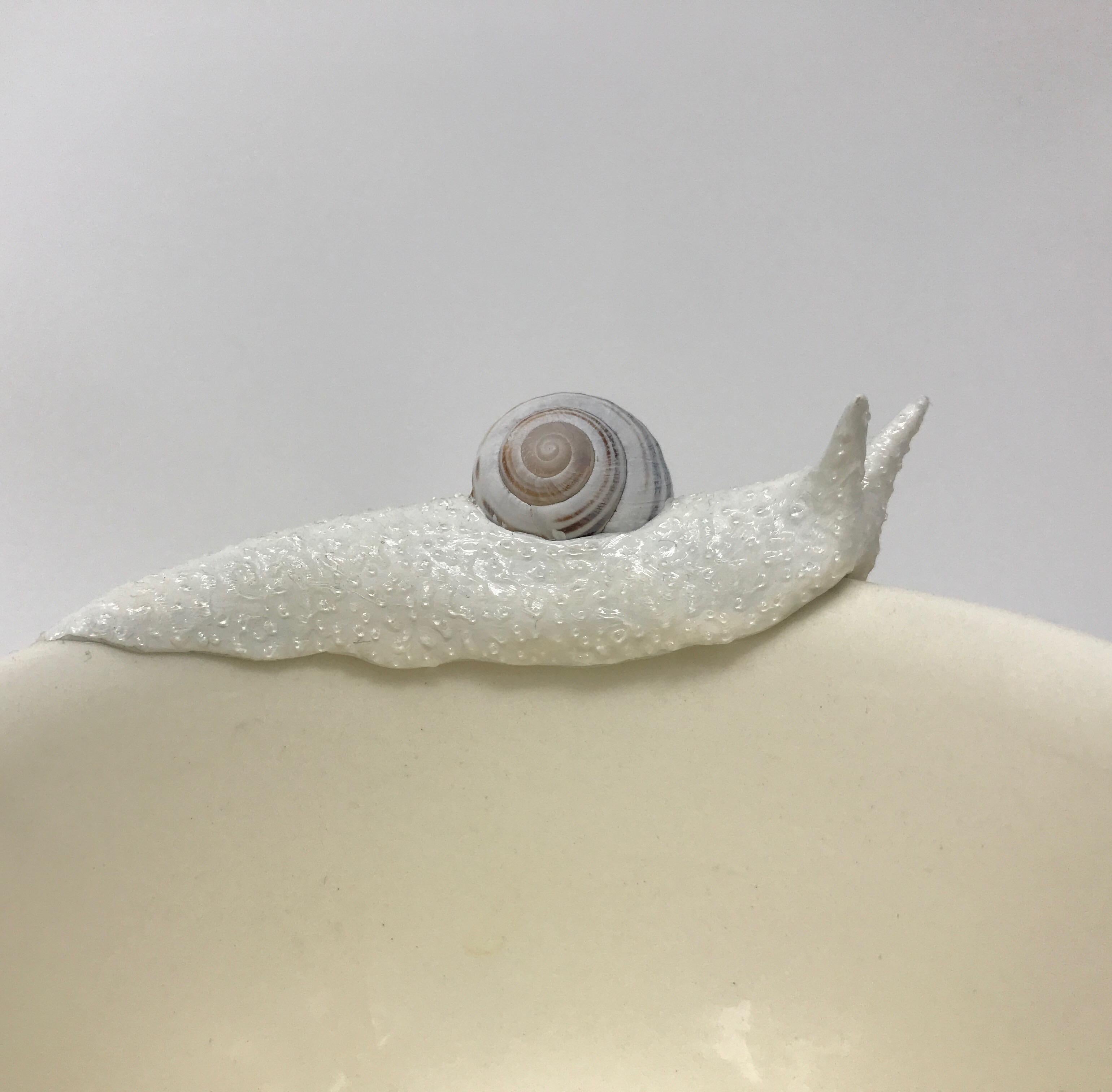 This piece is created with real found snail shells and a durable epoxy clay by New York artist, Bethany Krull. The artist sculpts the undulating snail bodies to circle the rim of this vintage yellow mug and saucer set. The glistening wet bodies are