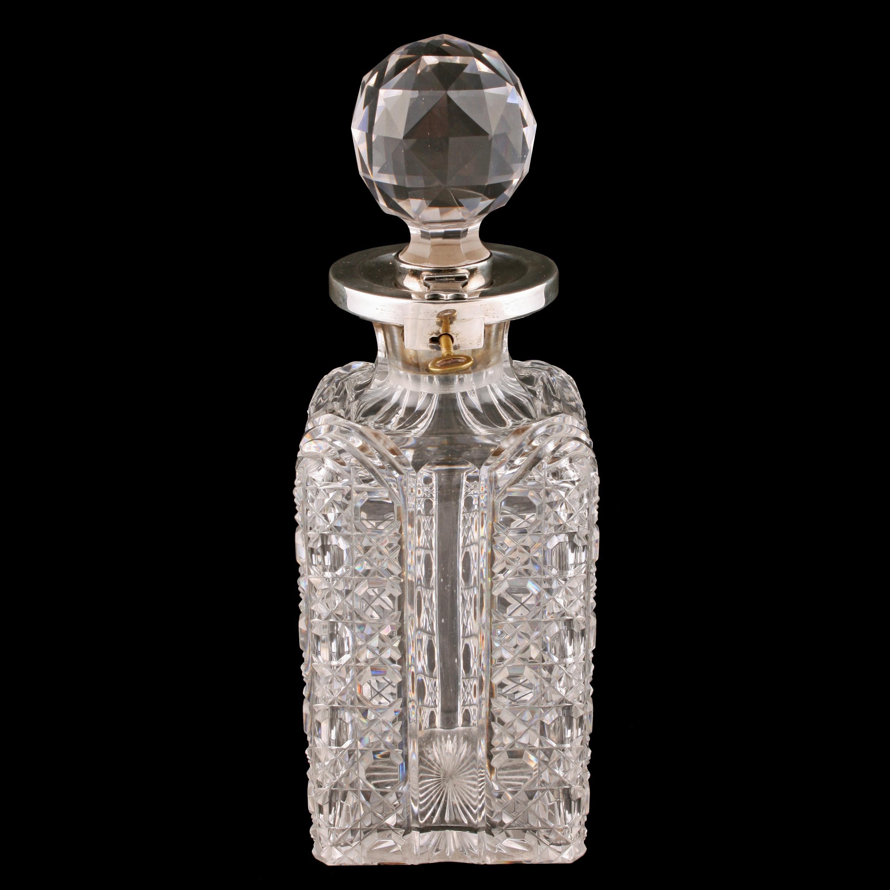 A Victorian Betjemann patent cut glass locking spirit decanter.

The square decanter has a cut body and a sterling silver collar on the neck with a lock and key.

The circular cut glass stopper is silver mounted with a hinged clasp that fits the