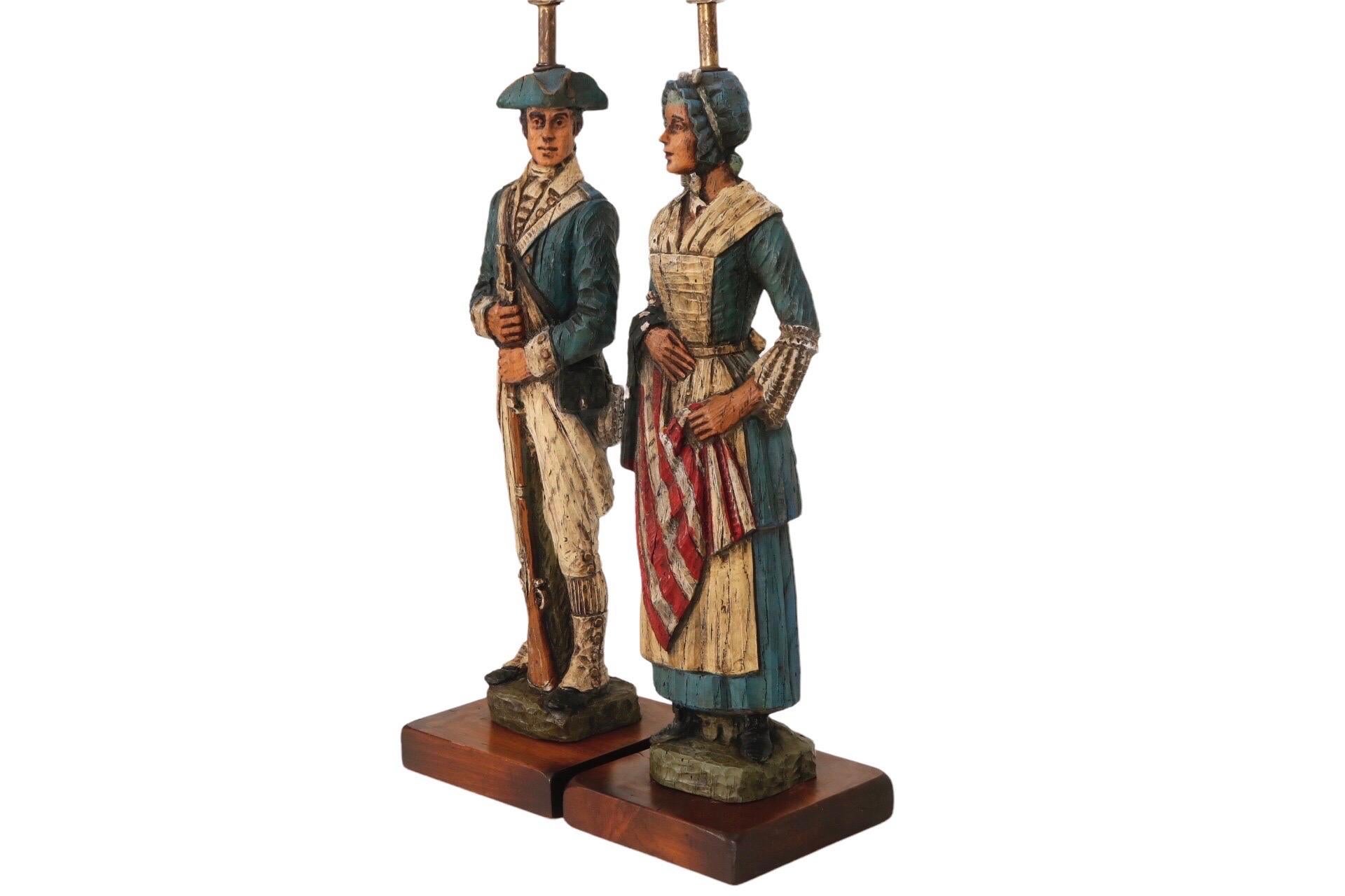 A set of two commemorative Bicentennial wooden table lamps made by Dunning Industries Incorporated. Carved figures in Revolutionary dress are Betsy Ross, the American upholsterer accredited with designing the first American flag, and a Minuteman in