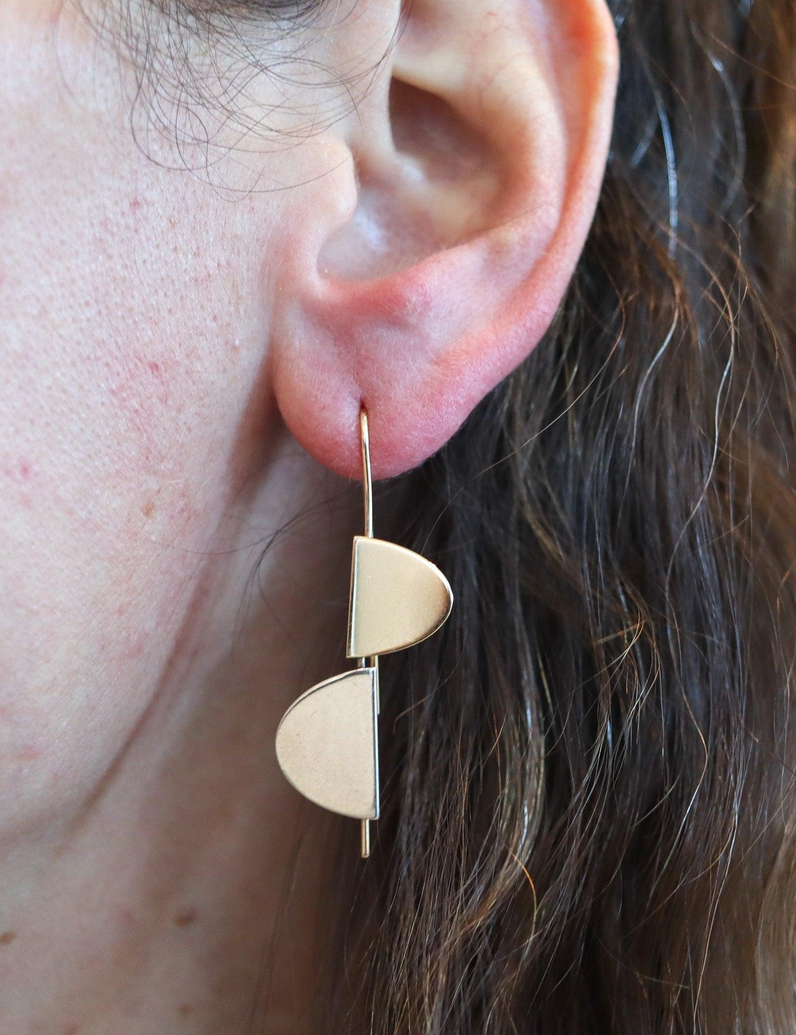 Geometric dangle earrings designed by Betty Cock. (1924-2025)

This is a great pair of geometric dangle drop earrings created by the artist-jeweler Betty Cooke. The sculptural earrings have been crafted with two semi-oval elements, made up in solid