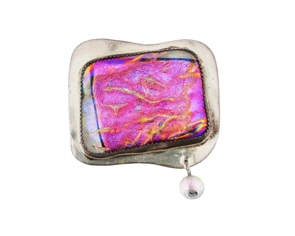 A vintage sterling silver and dichroic glass pin brooch. The piece is garnished with an iridiscent glass bead. Marked Betty Helfen Sterling on the backside. Total Weight: 27.2 grams. Unusual Designer Jewelry And Statement Lapel