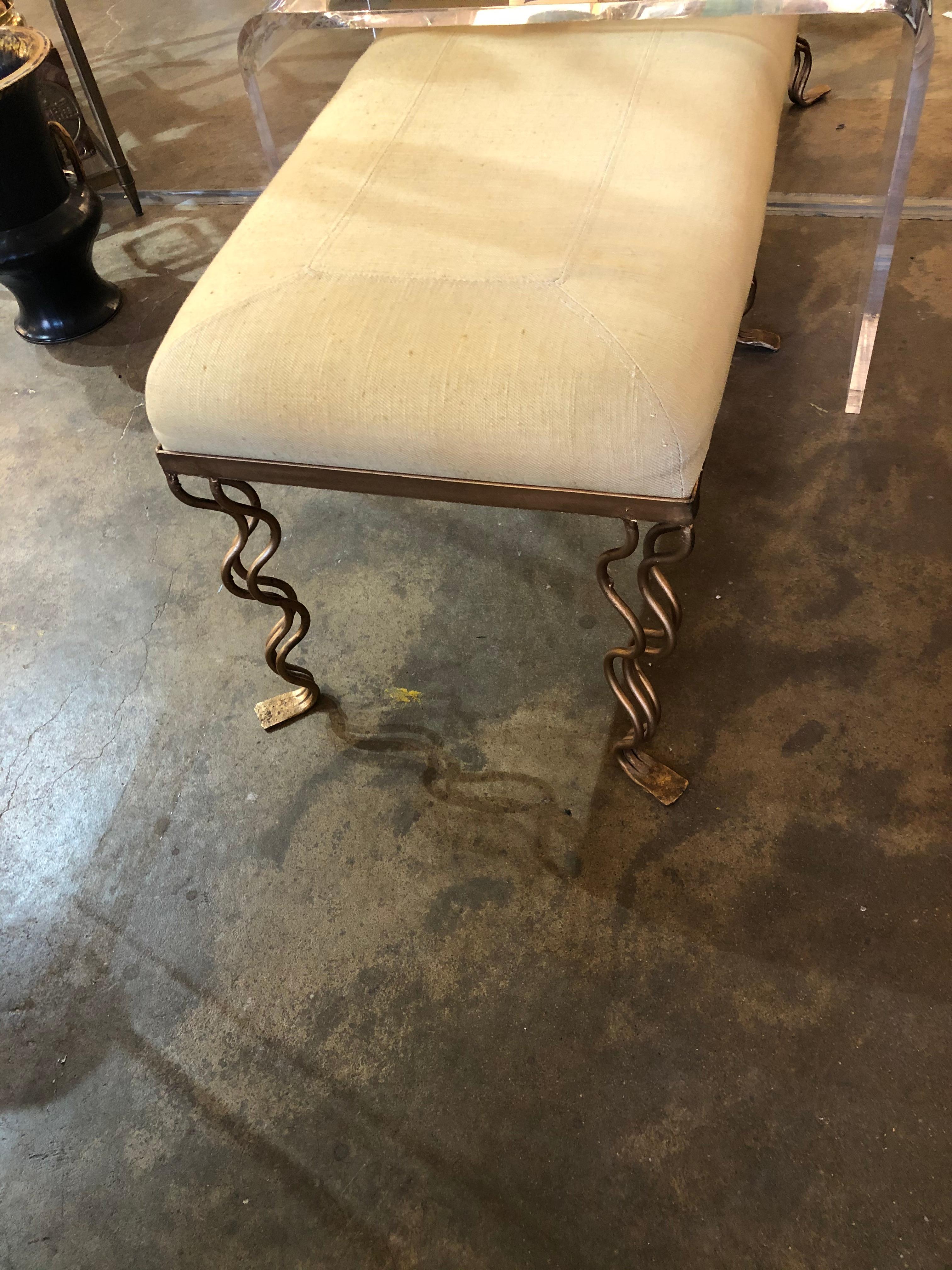 A 20th century gilt iron bench with ecru linen stitched upholstery ending in 