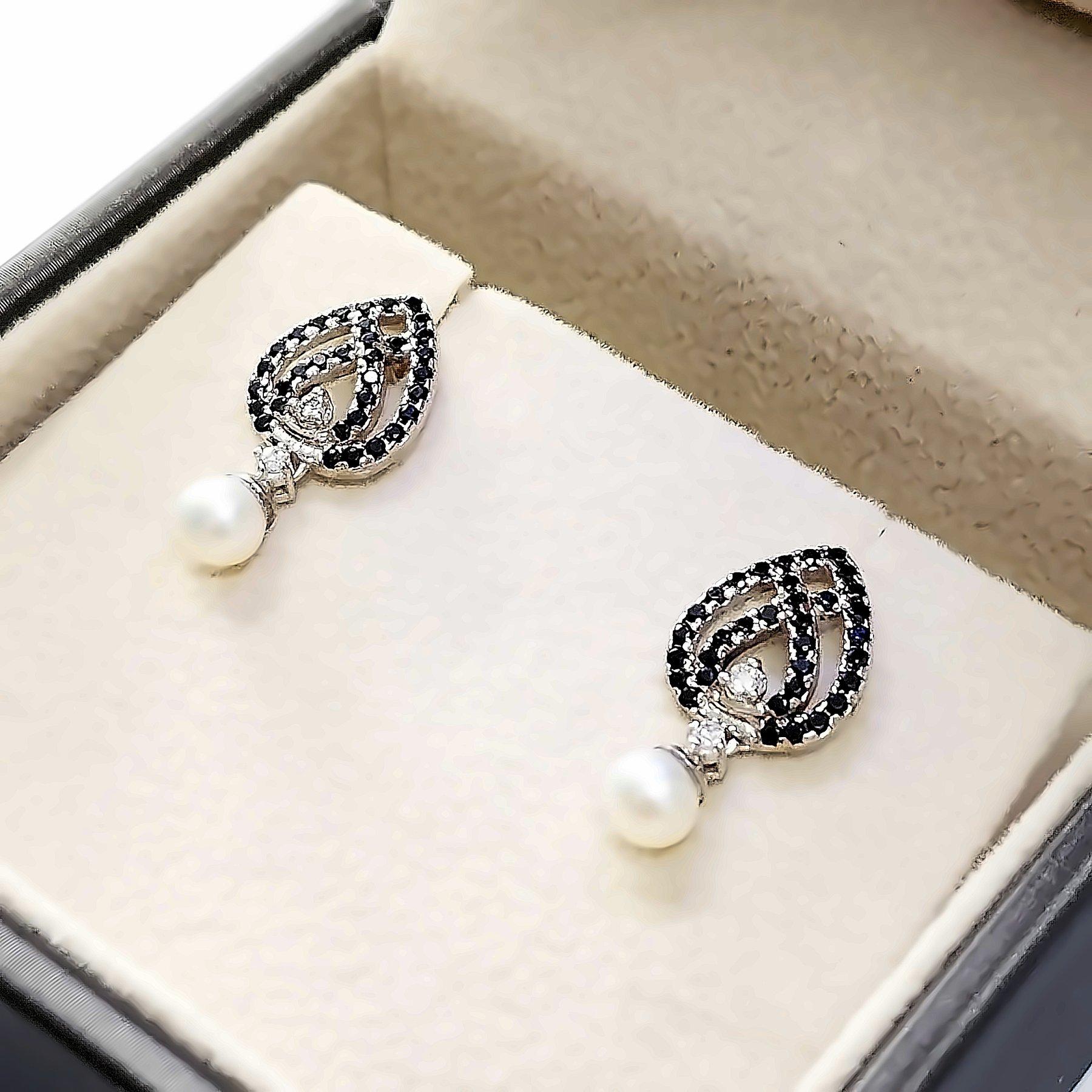 The earrings are made of 14K white gold and each earring is set with round pearl , 2 natural Diamonds and 34 natural Spinels stones.
A total of 2 Pearls, 4 Diamonds witth a total weight of 0.15 ct,  and 68 Spinels with a total weight of 0.68