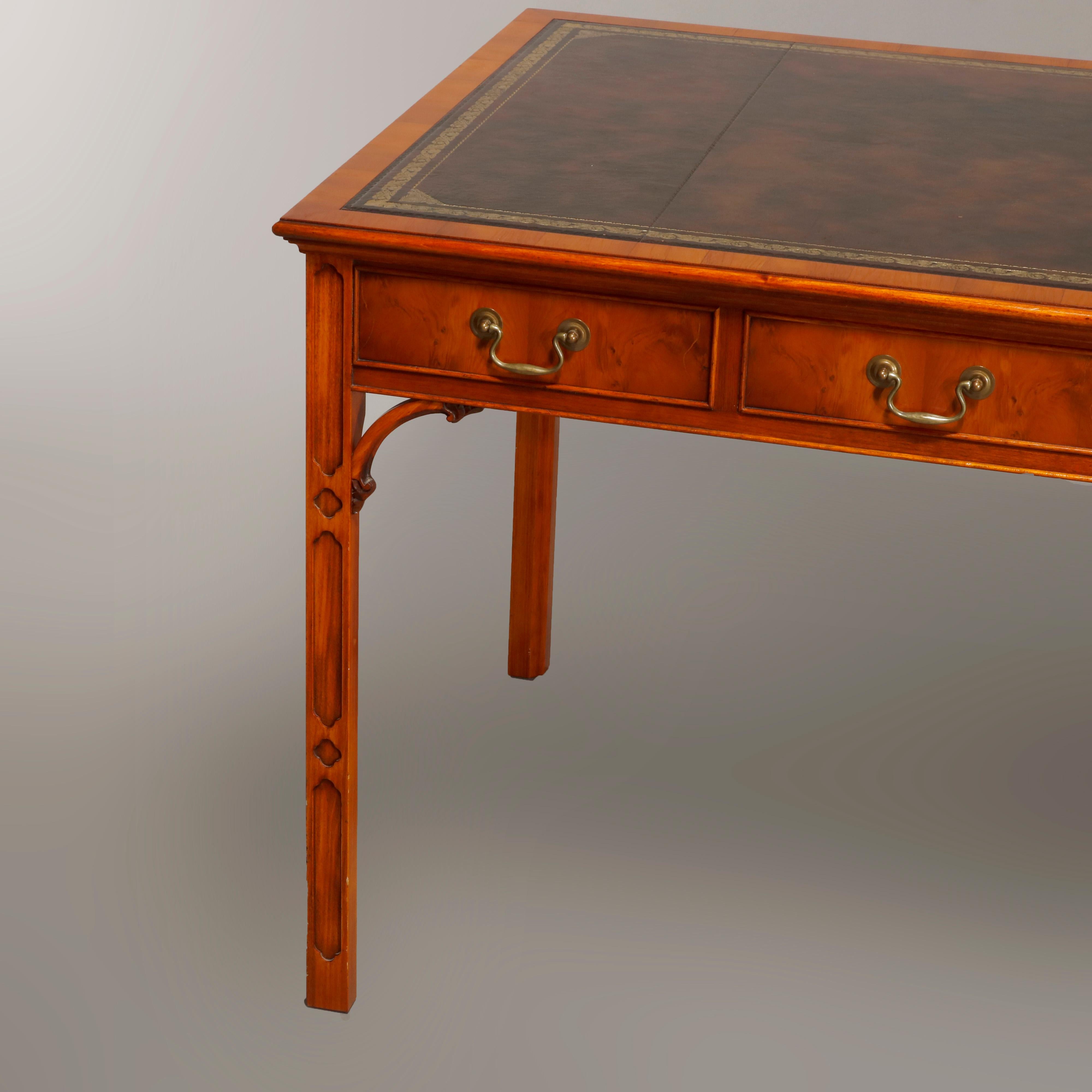 An antique English Chinese Chippendale flat top writing desk by Bevan Funnell Reprodux offers mahogany and olivewood construction with gilt decorated leather top surmounting carved mahogany base with three drawers and side panels having olivewood