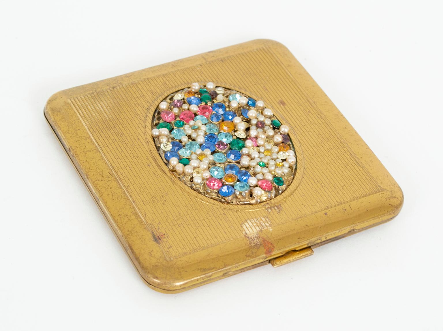 A throwback to the days when a woman touched up her lipstick at the table, this jeweled compact throws prisms in even the dimmest light. Its oval center marquis is literally crusted with colored rhinestones and seed pearls, and a gentle click opens