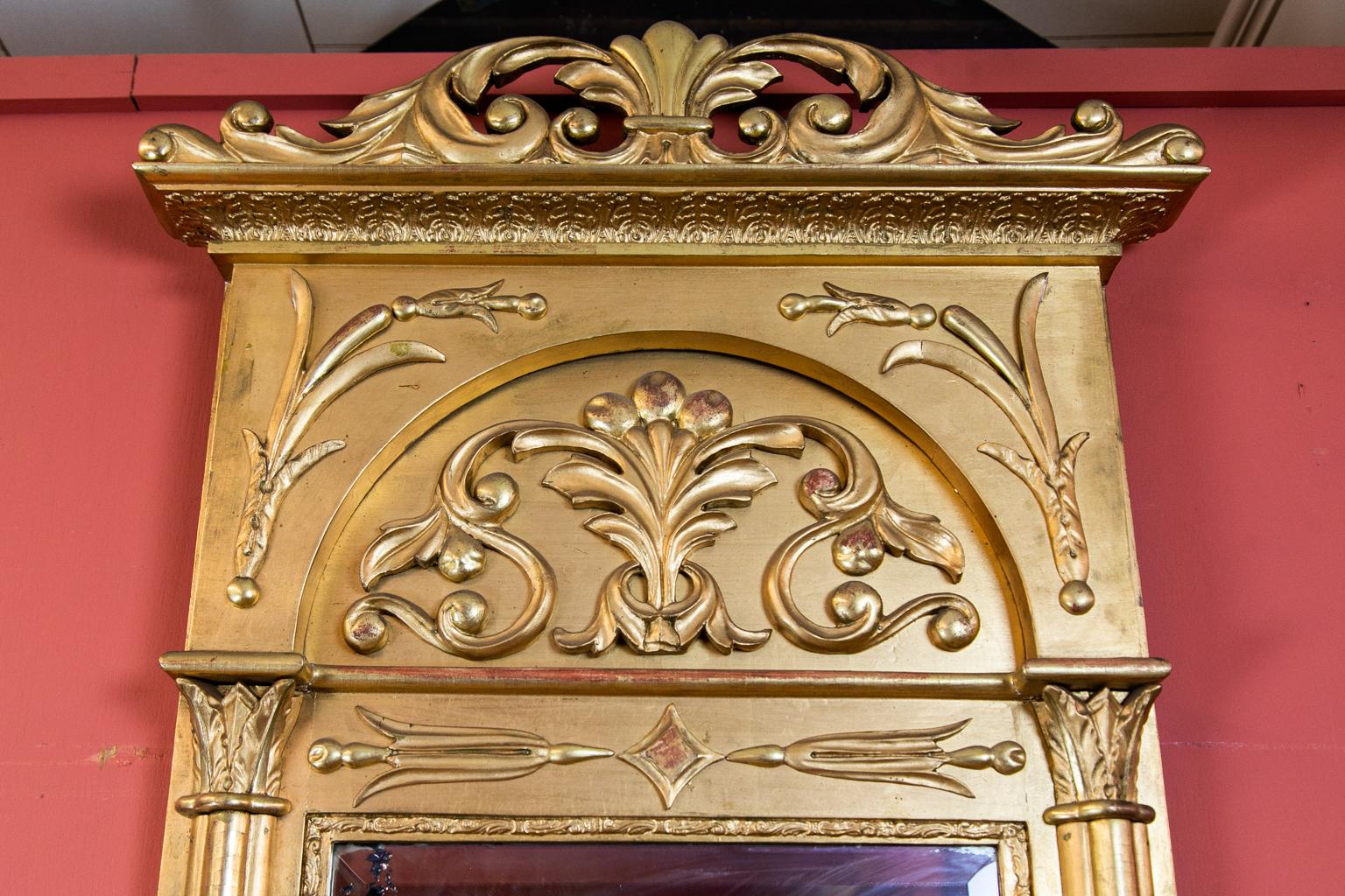 Beveled English gilt Regency mirror, the sides framed with cluster columns topped with acanthus leaf capitals. The crest has a stylized fleur-de-lis surrounded by floral arabesques. It has some spots of deterioration in the silvering.
  