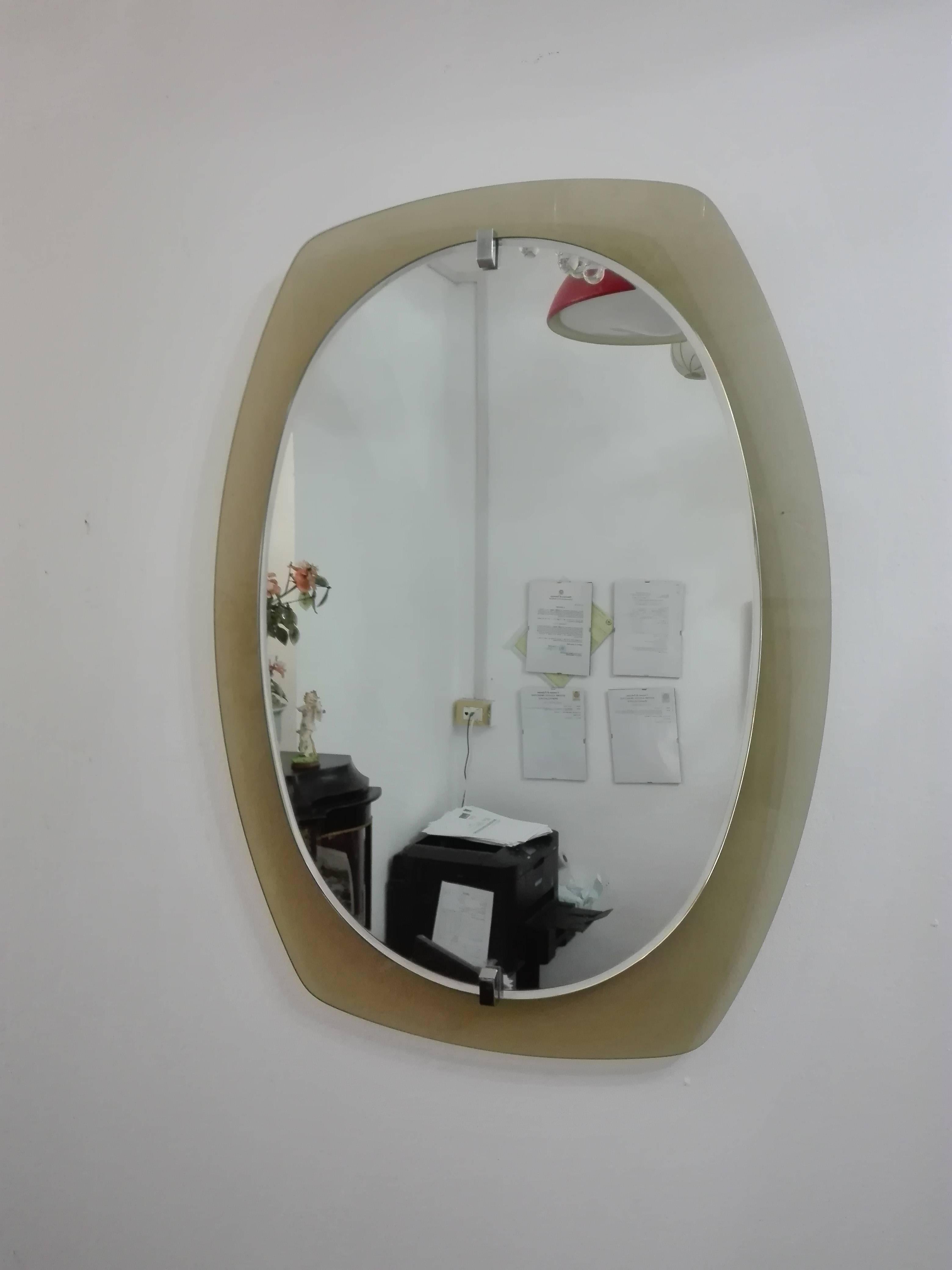 This beveled mirror was produced by Veca in the 1960s. It features a caramel glass frame and nickel plated brass screw heads.