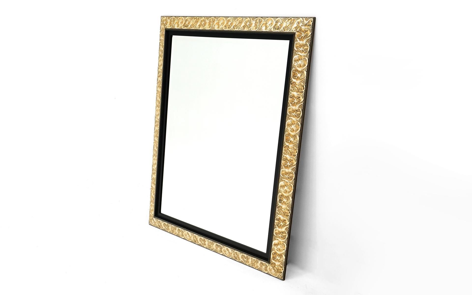 Repoussé (reverse hand hammered aluminum frame) wall mirror with beveled edge. In as close to new condition as things come. The aluminum is anodized to a soft brass color. Genko leaf motif.