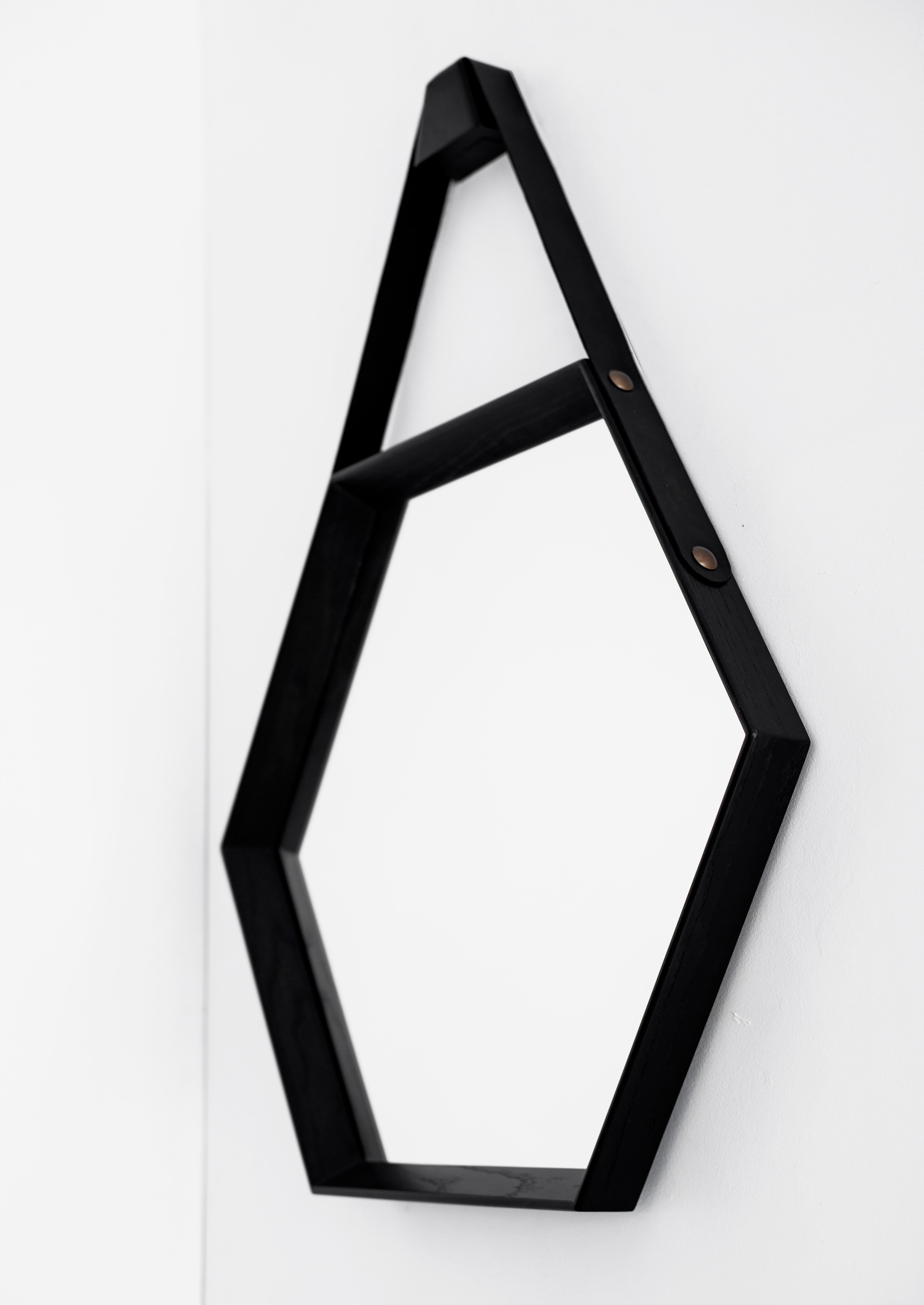 Miroir hexagonal en chêne de fabrication récente, avec finition ébène et détail en cuir noir attaché à des clous. Un design propre et moderne. Plusieurs quantités et finitions disponibles.
Le miroir mesure 28