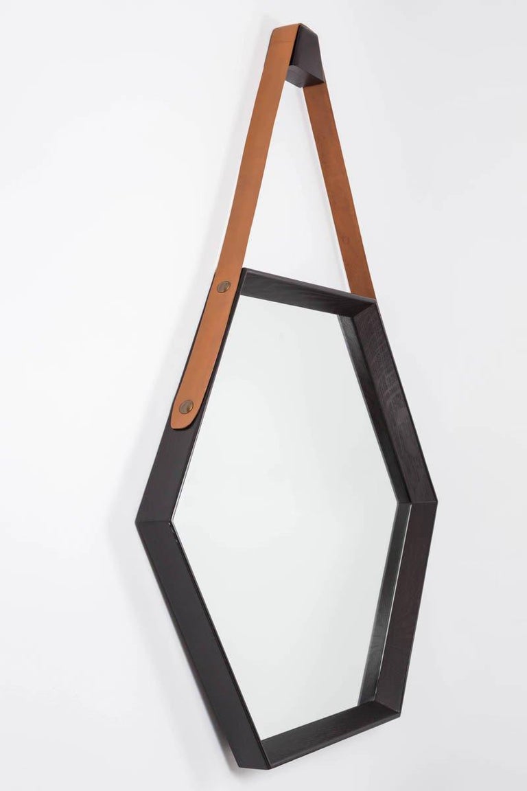 Newly produced oak hexagon mirror with ebony finish and leather strap detail attached to studs.  Clean and modern design. Multiple quantity and finishes available.