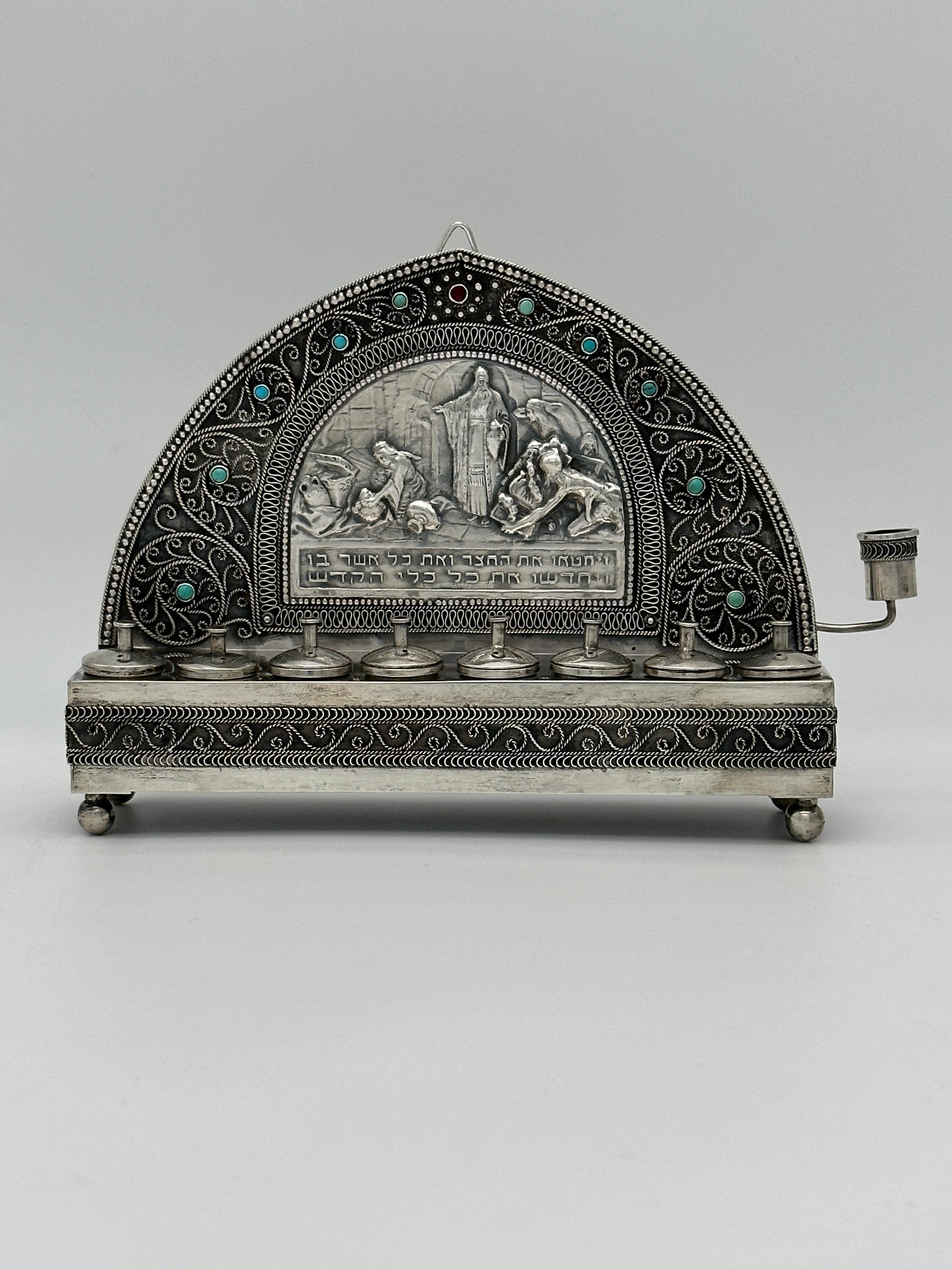 Una lampada di Hanukkah in argento realizzata da Yehia Yemini a Gerusalemme intorno al 1920 è un affascinante pezzo di Judaica. Yehia Yemini era nota per i suoi intricati e dettagliati lavori in argento. Questa lampada presenta disegni elaborati,