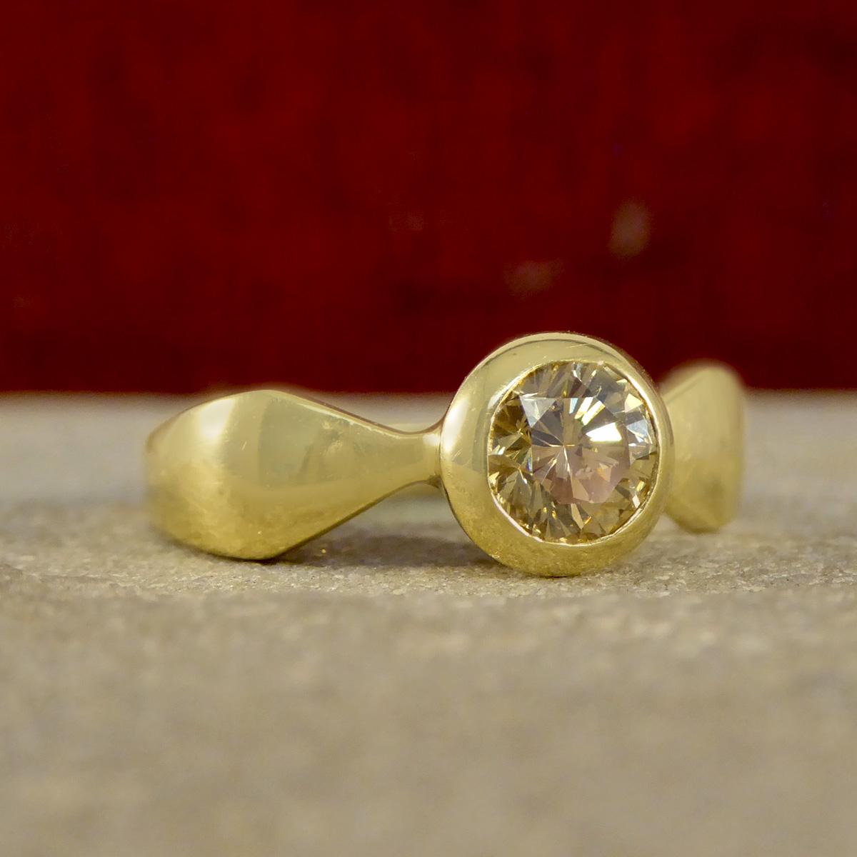 Cette élégante bague en or jaune 18ct sertie d'un diamant châtaigne de 0,60ct est un véritable témoignage de style et de sophistication intemporels. Avec en son cœur un captivant diamant rond de 0,60ct taillé en brillant, cette bague respire la