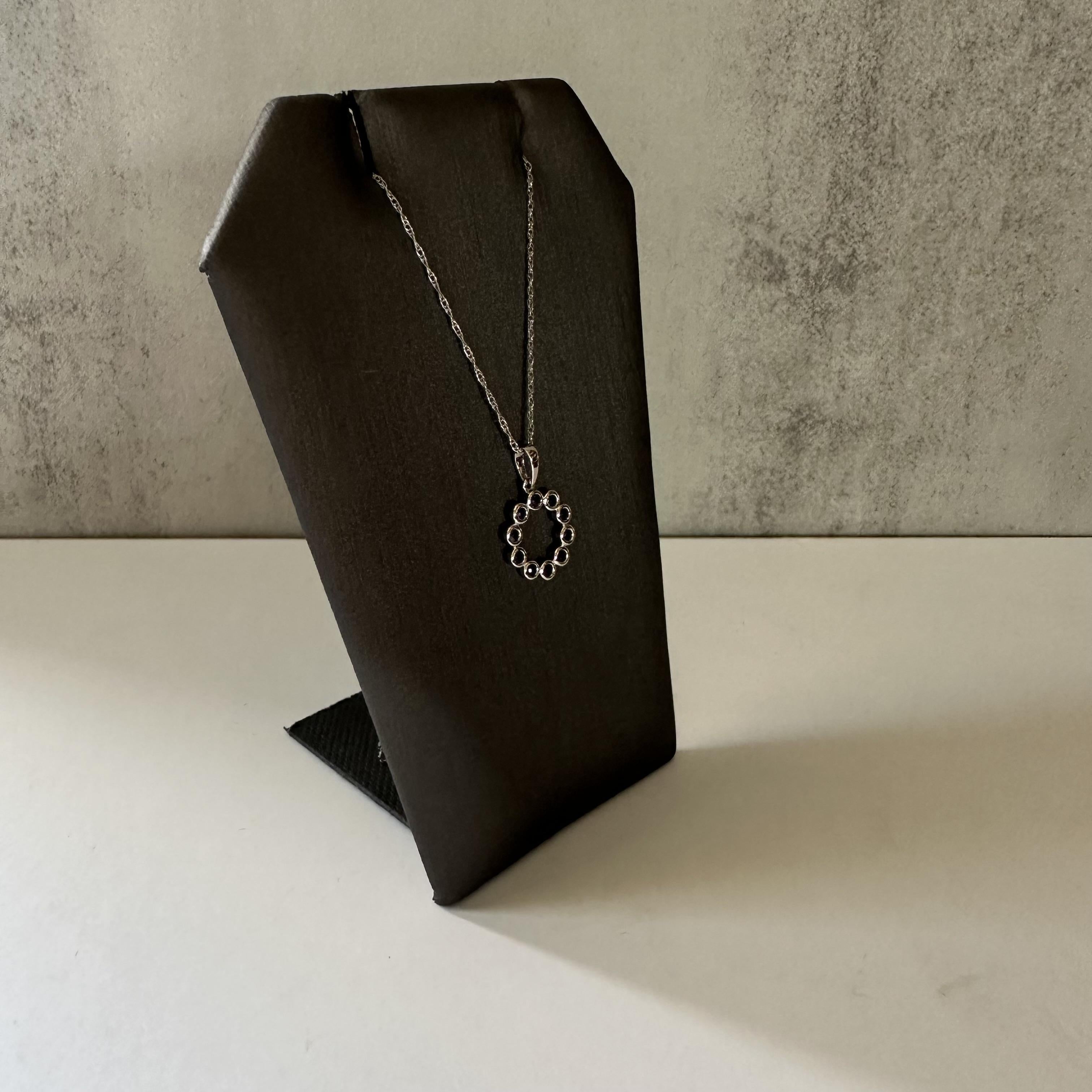 Discover the refined simplicity of this elegant necklace. Featuring a circular pendant composed of interlinked rings, this piece offers a modern and minimalist aesthetic. The pendant hangs gracefully from a delicate chain, creating a harmonious