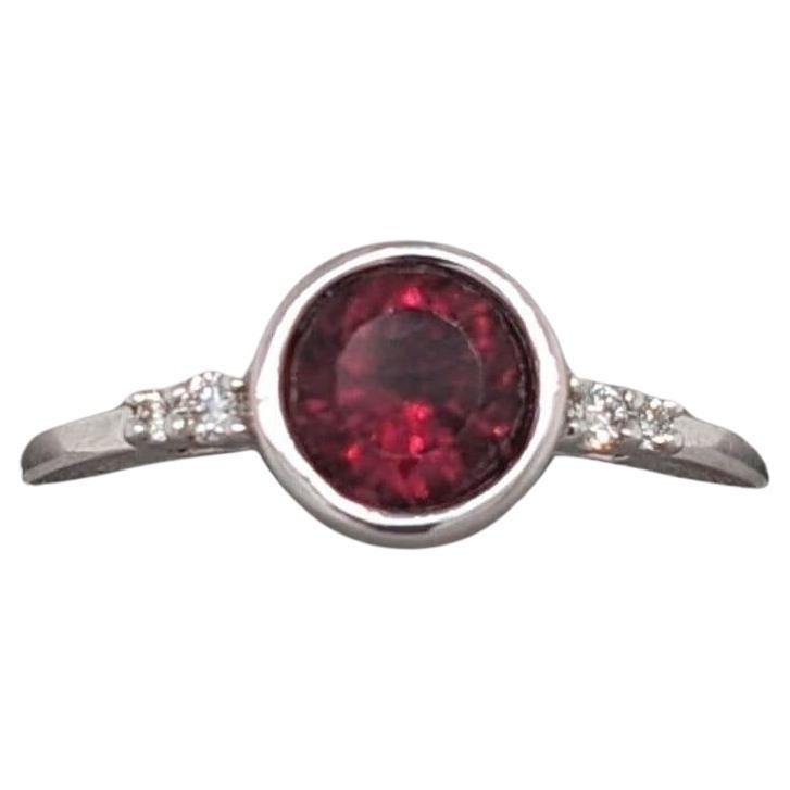 This beautiful ring features a striking deep red rubellite bezel set in 14k white gold with natural earth mined diamond accents. A statement ring design perfect for an eye catching engagement or anniversary. This ring also makes a beautiful