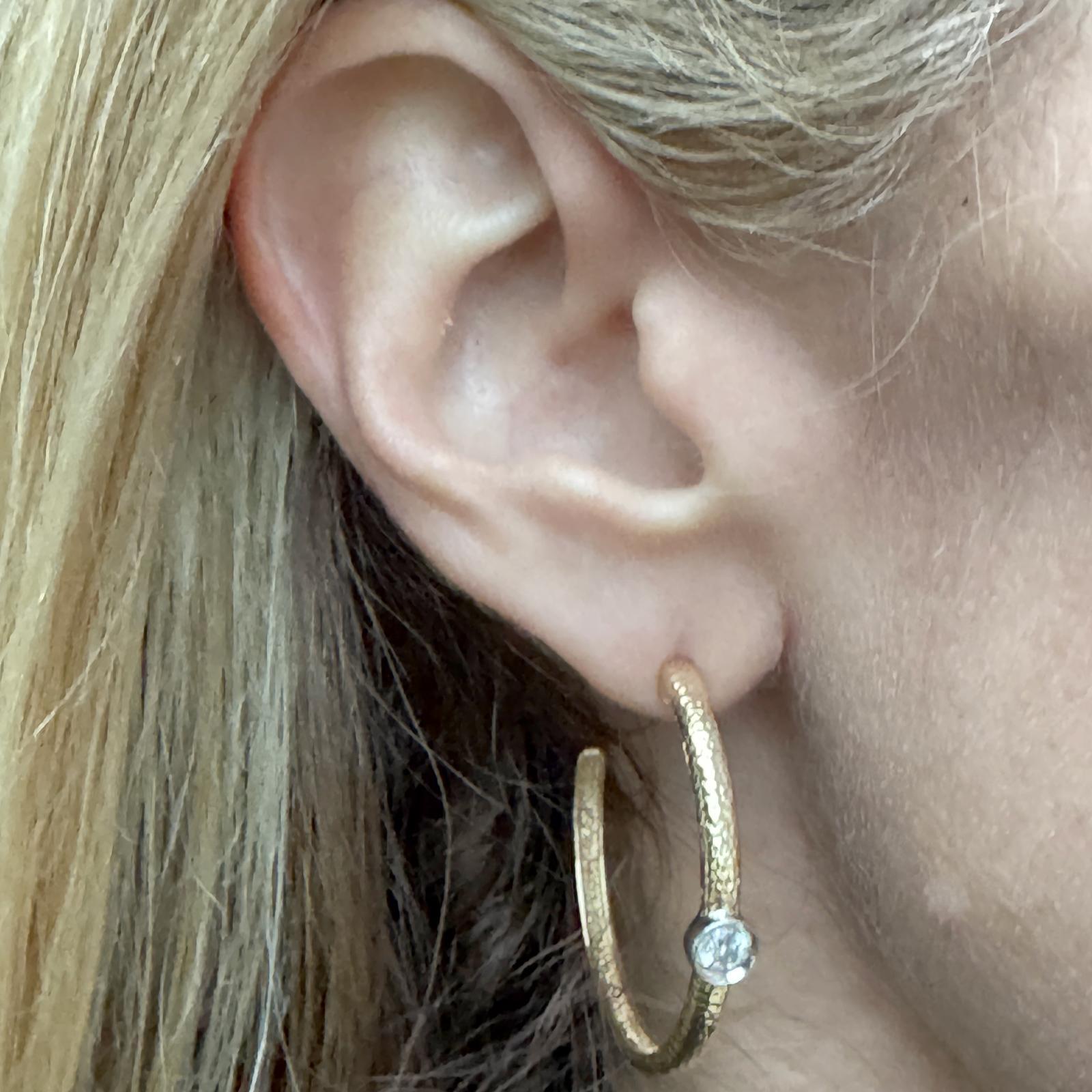 Diese eleganten Diamantohrringe aus 14 Karat Gelbgold haben ein klassisches 1,5-Zoll-Design mit zwei runden Diamanten im Brillantschliff mit insgesamt 0,20 Karat in der Lünette. Die Diamanten, die in der Farbe H-I und in der Reinheit SI eingestuft